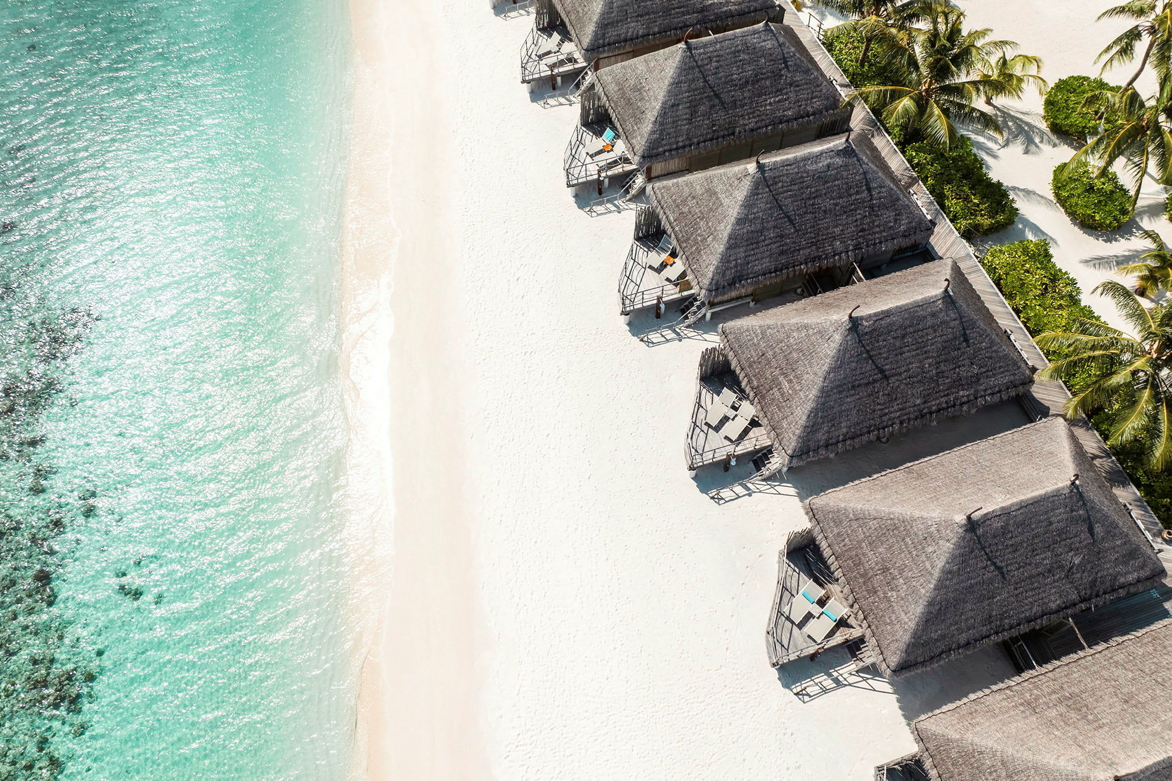 Strand med turkist vann og flere strandnære bungalower. (AI-generert tekst)