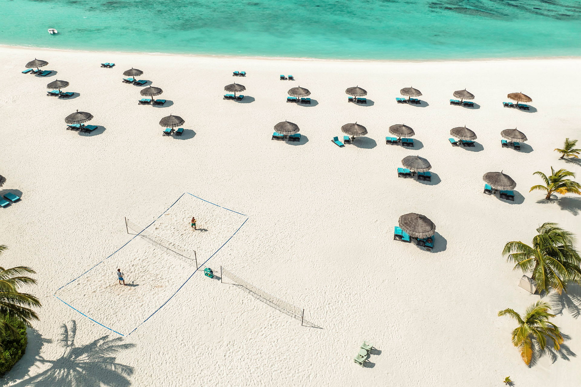 Strand med parasoller, solsenger og et volleyballnett. (AI-generert tekst)