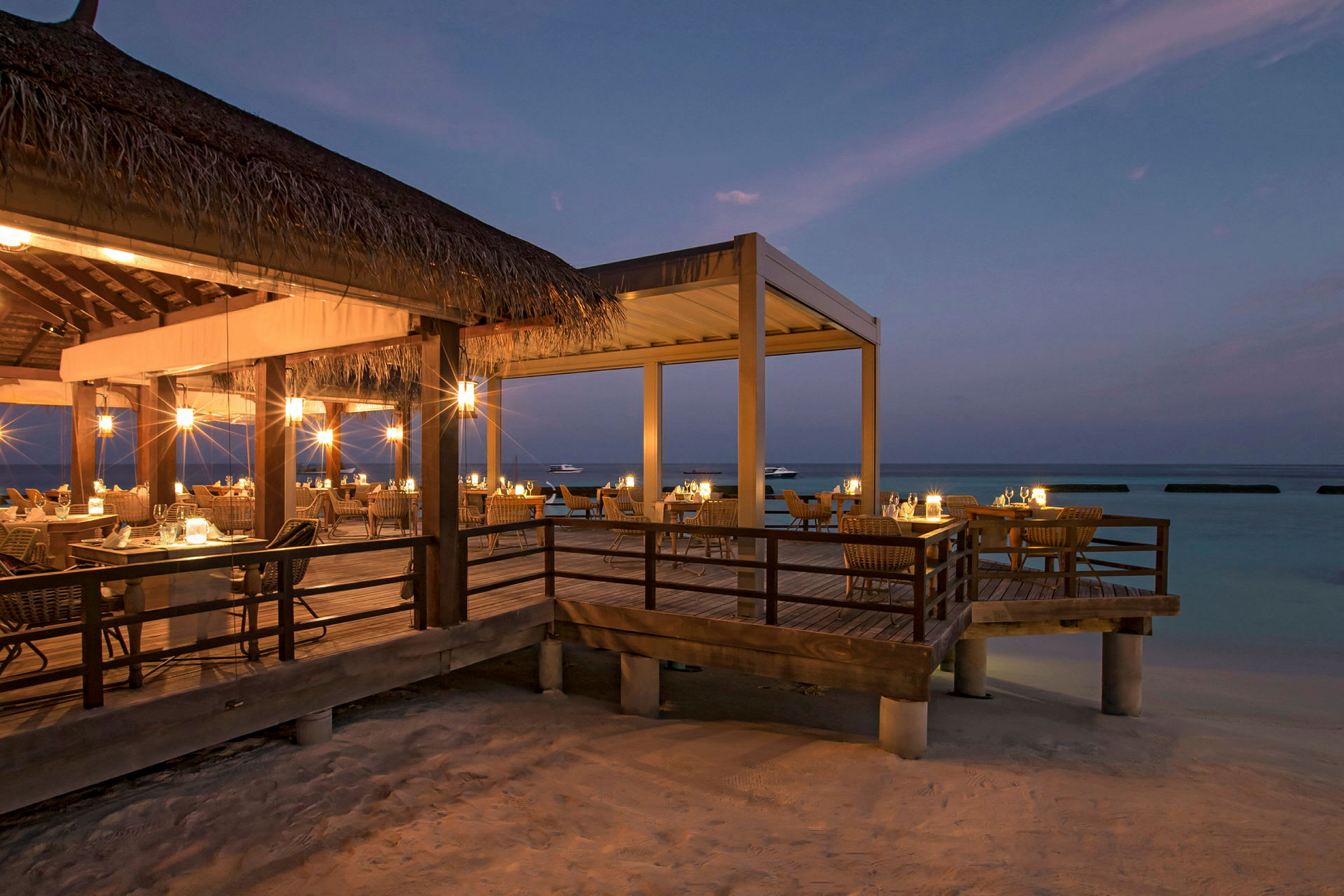 Restaurant med utendørs servering ved stranden i skumringen. (AI-generert tekst)