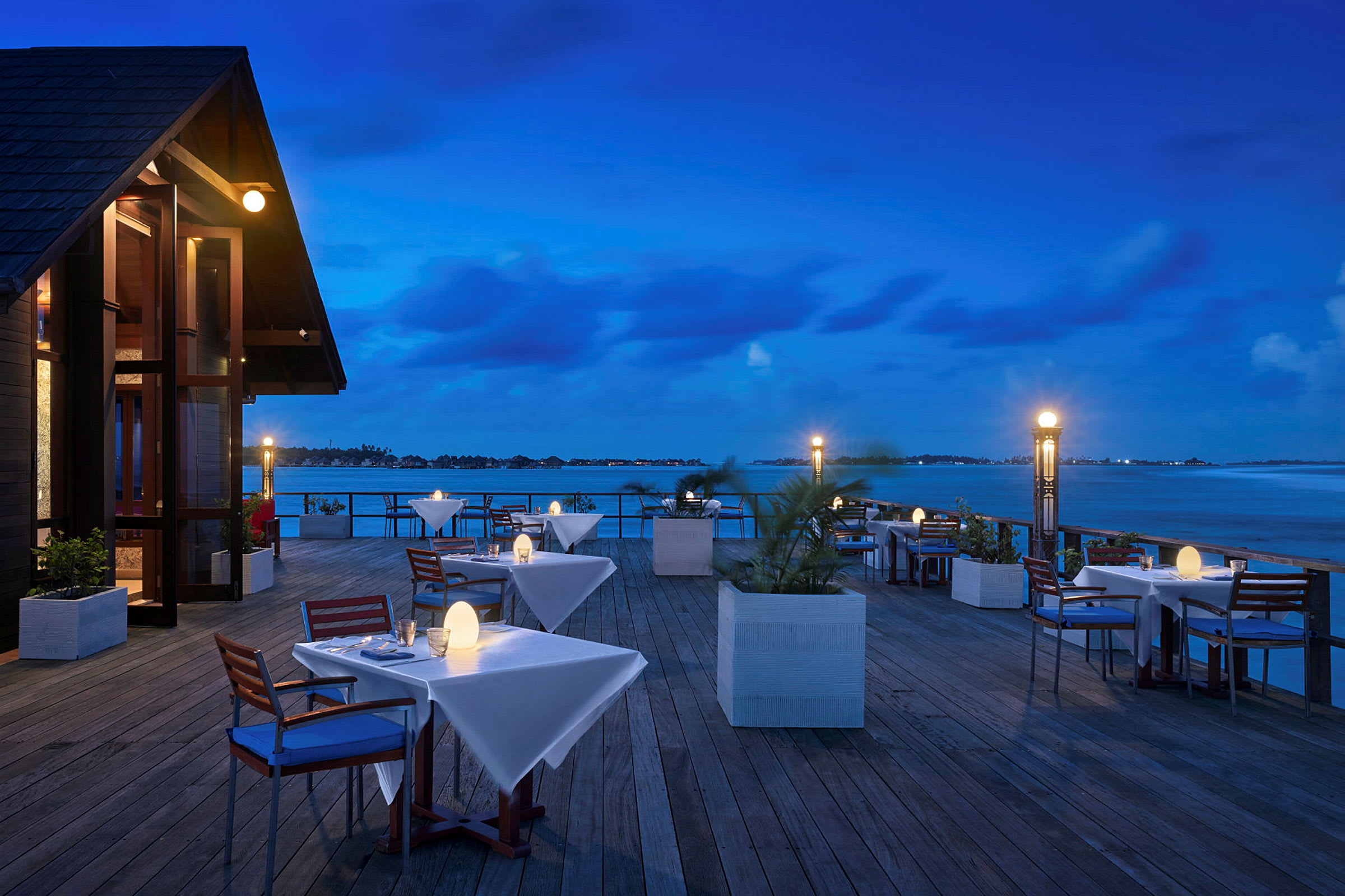 En dekket restaurant med uteservering ved vannet om kvelden. (AI-generert tekst)