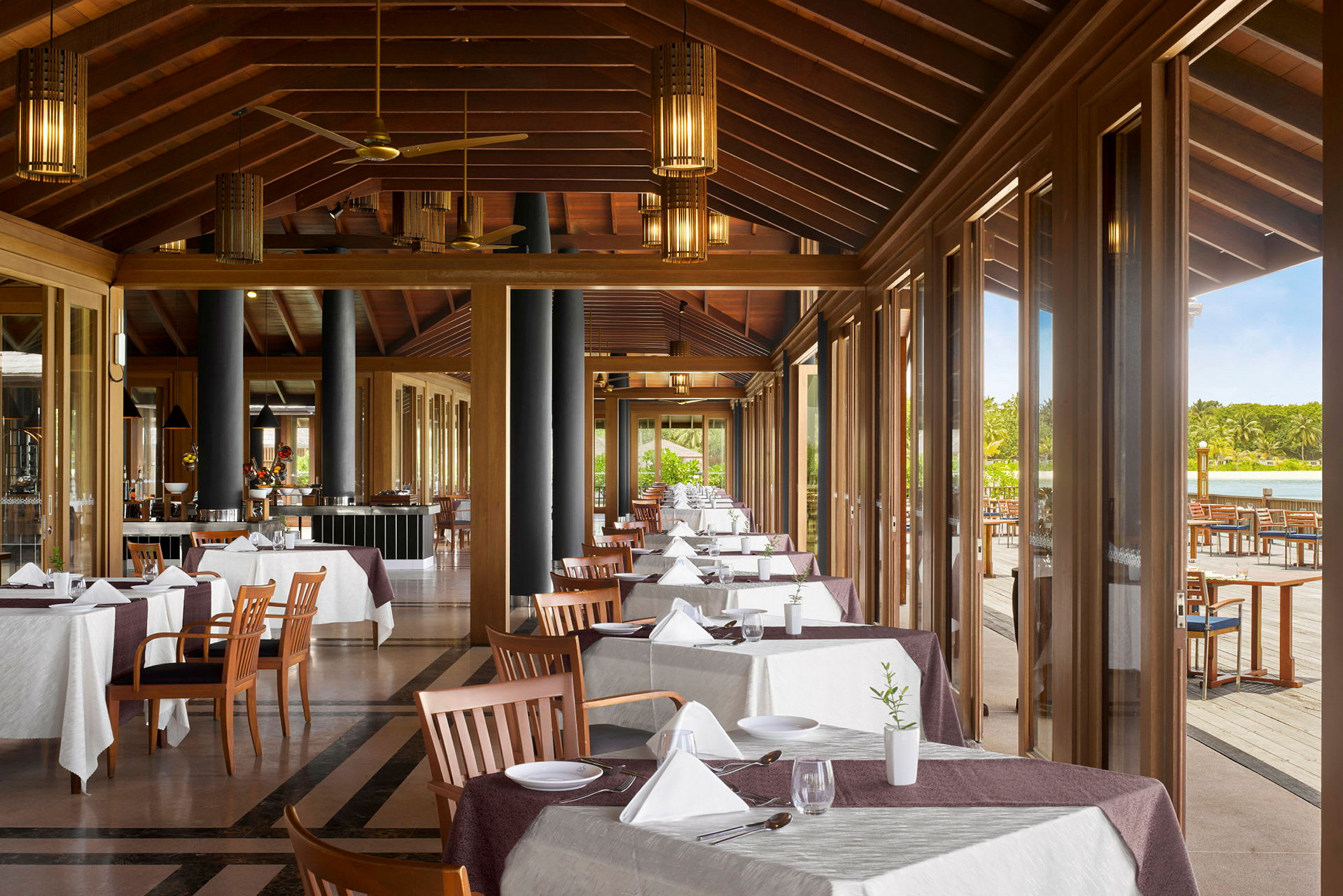 En restaurant med dekkede bord og store vinduer som vender mot en terrasse. (AI-generert tekst)