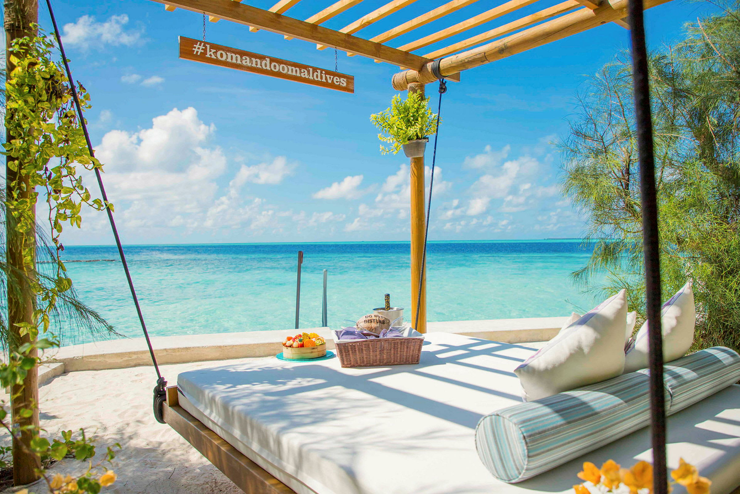 En solseng med mat og drikke ved en strand med turkist hav og himmel. (AI-generert tekst)