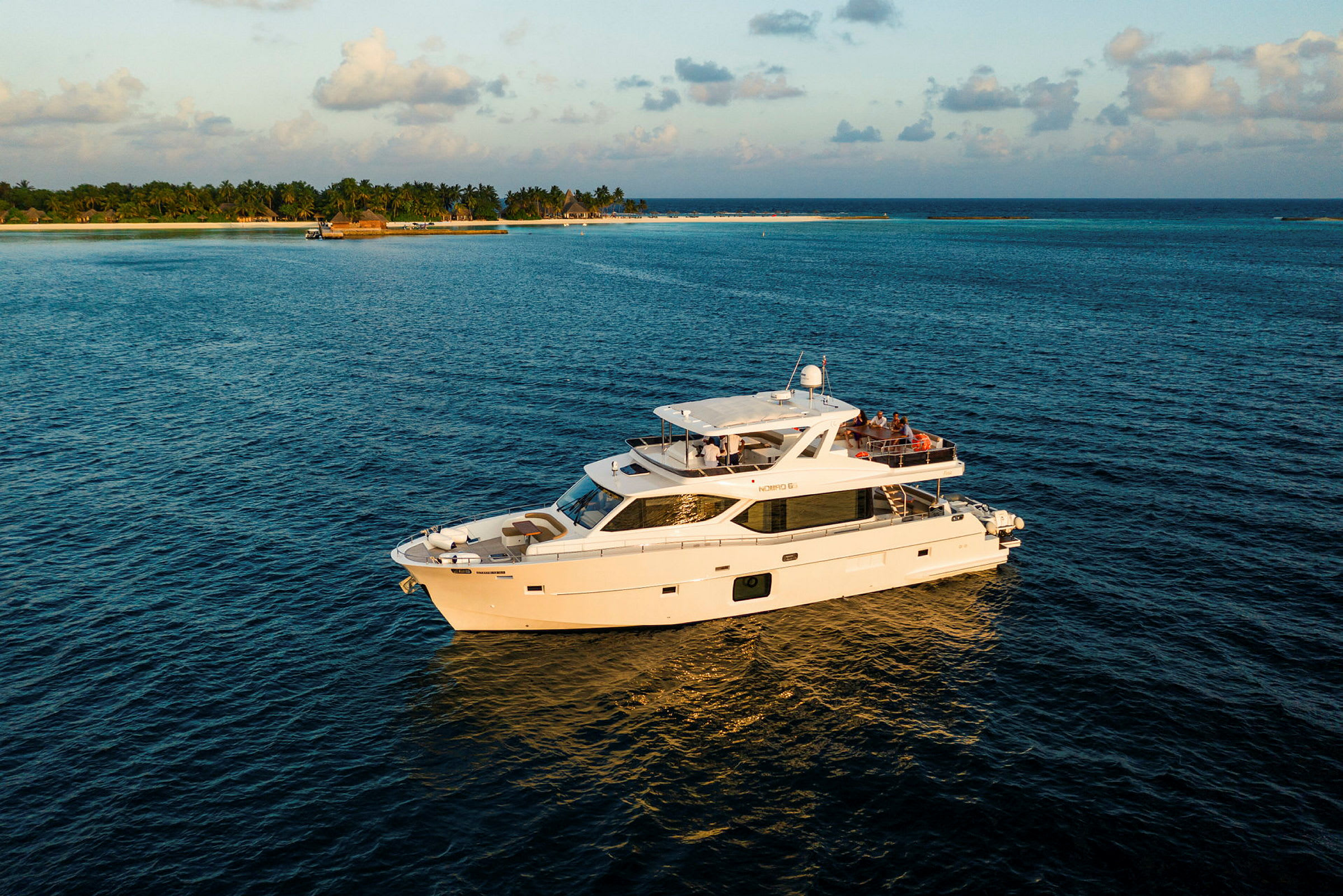 En hvit yacht flyter på vannet med en øy i bakgrunnen. (AI-generert tekst)