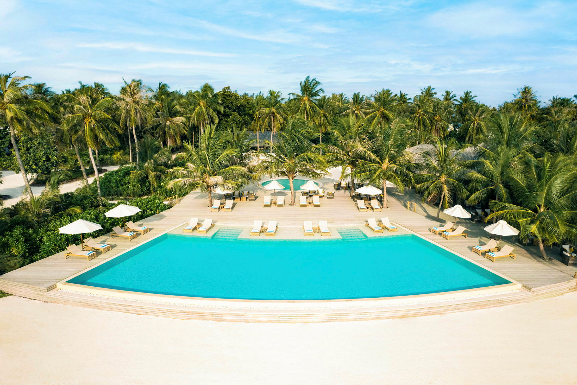 Basseng med solsenger og parasoller, omgitt av tropiske palmer. (AI-generert tekst)