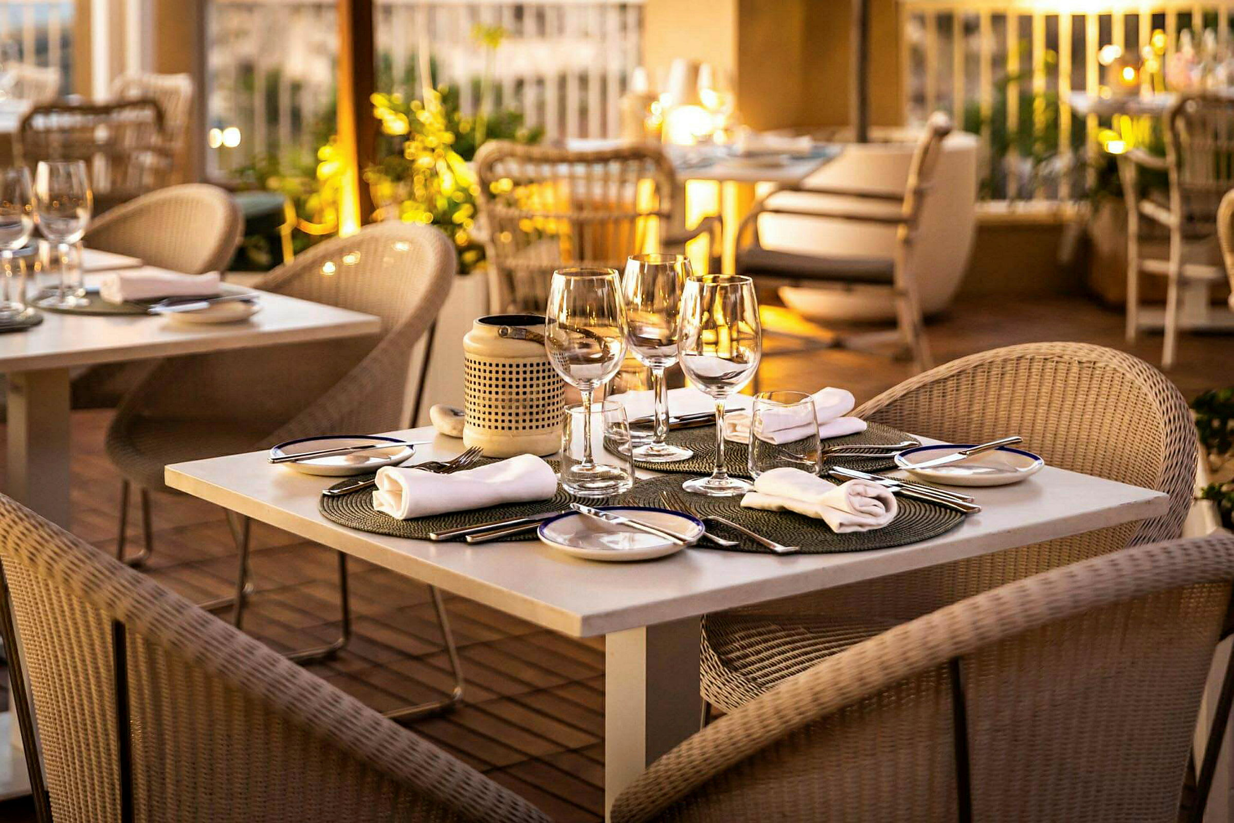 Et bord på en elegant restaurant med glass, bestikk og tallerkener. Mykt lys og en innbydende atmosfære. (AI-generert tekst)
