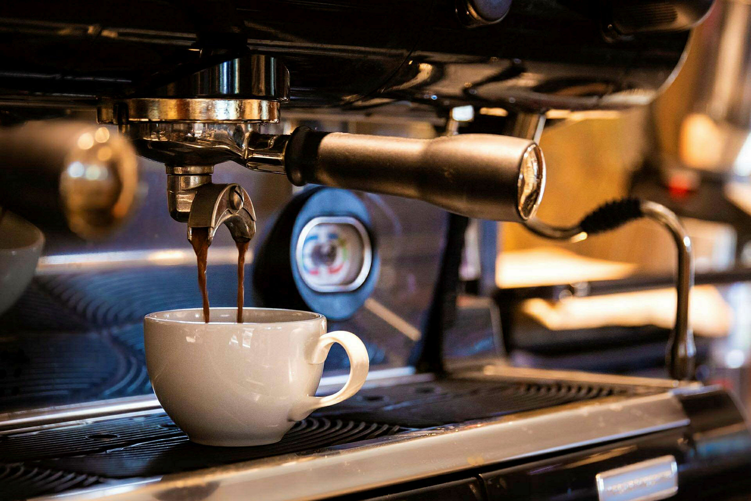 En espressomaskin brygger kaffe som renner ned i en hvit kopp. (AI-generert tekst)