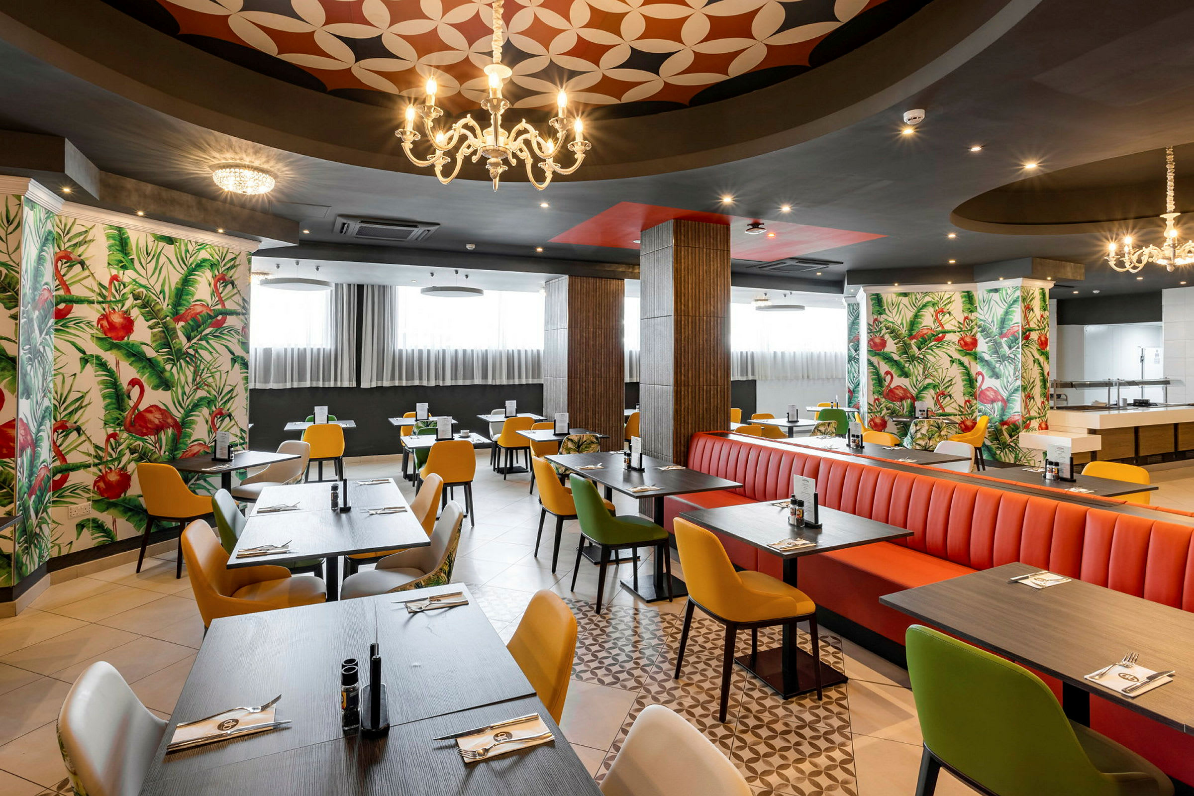 Restaurant med fargerike stoler og bord, dekorert med flamingo-mønstret tapet. (AI-generert tekst)