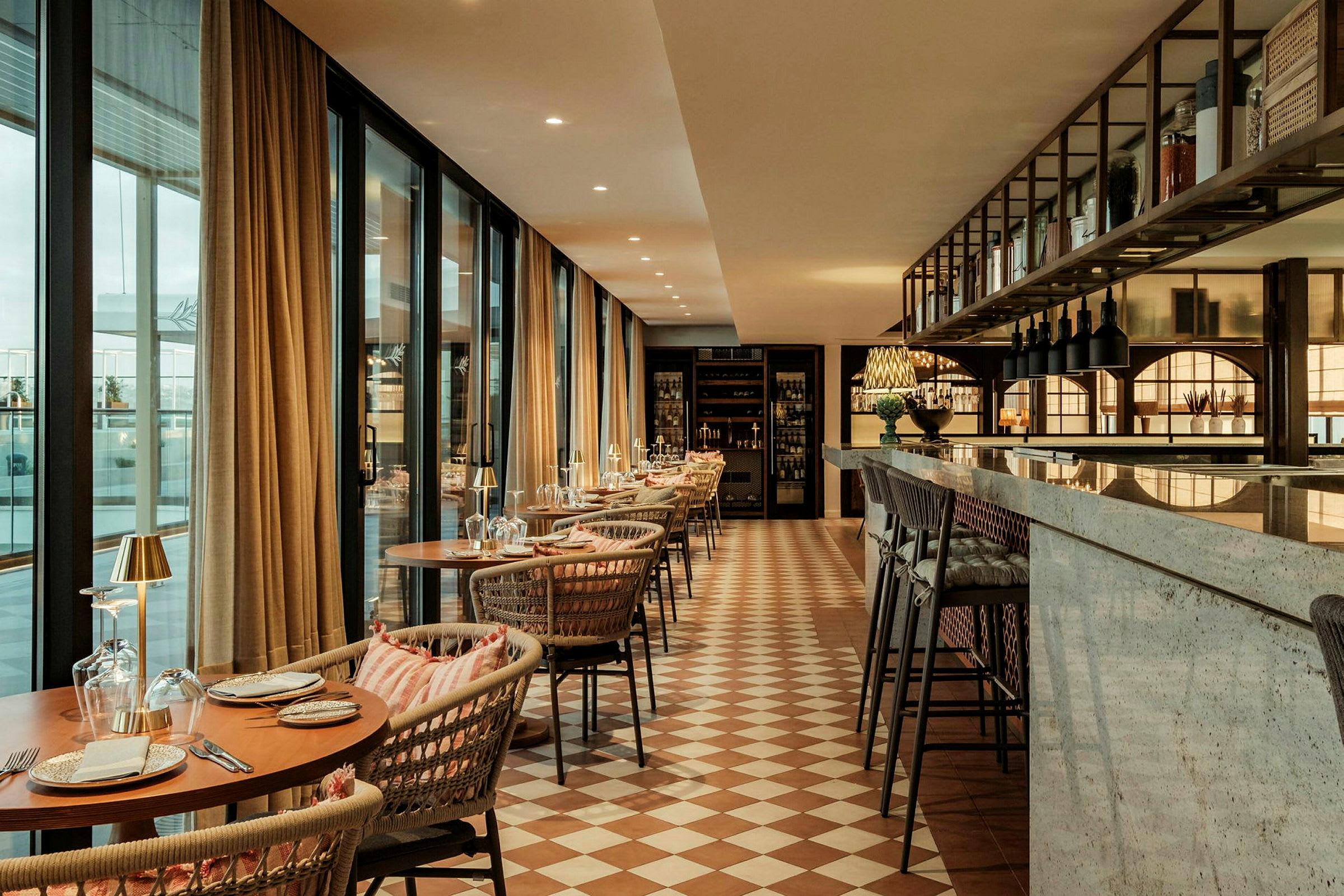 En elegant innredet restaurant med dekkede bord, komfortable stoler, store vinduer og en marmordisk. (AI-generert tekst)