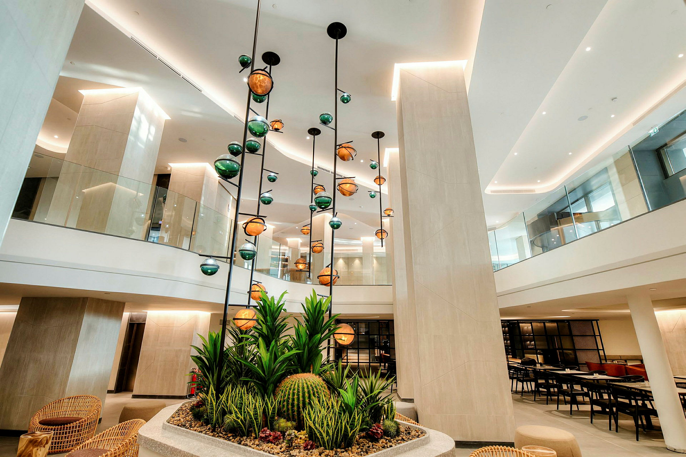 Bilde av en moderne hotellobby med hengende lamper og dekorative planter i forgrunnen. (AI-generert tekst)