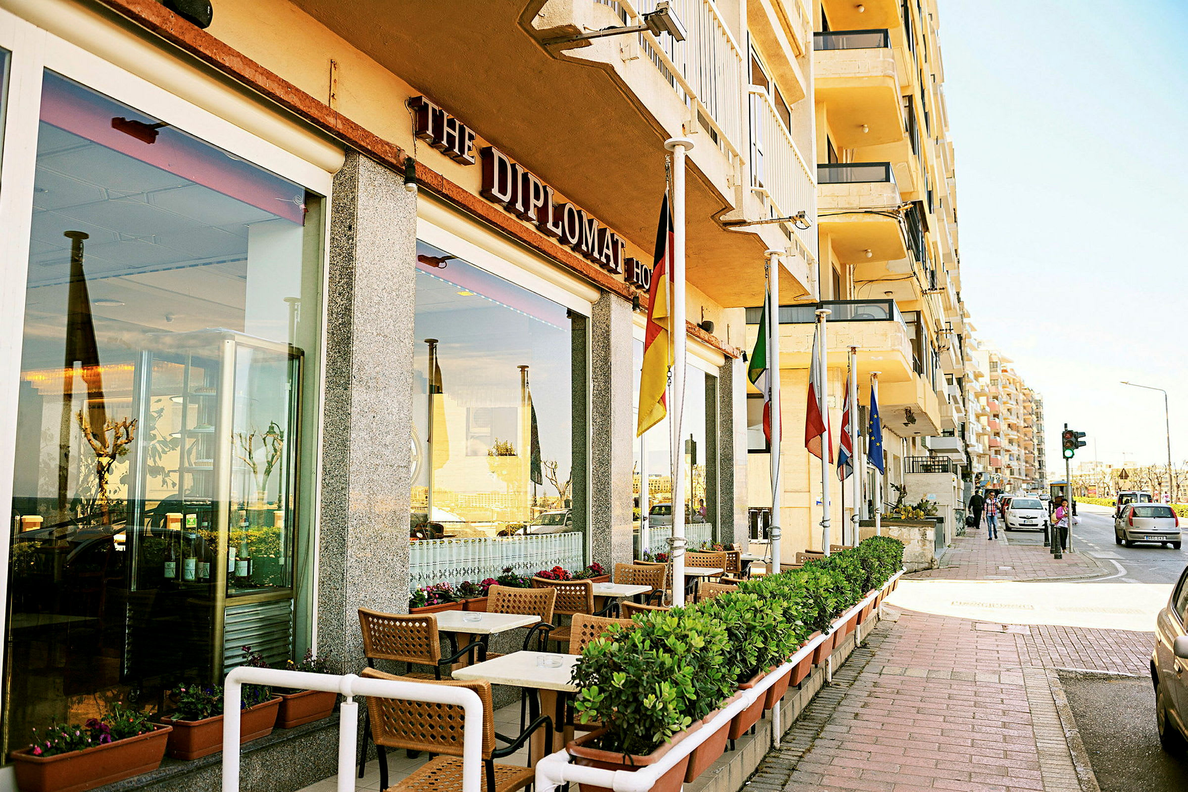 Restaurant med uteservering og ulike flagg ved inngangen langs en fortau. (AI-generert tekst)
