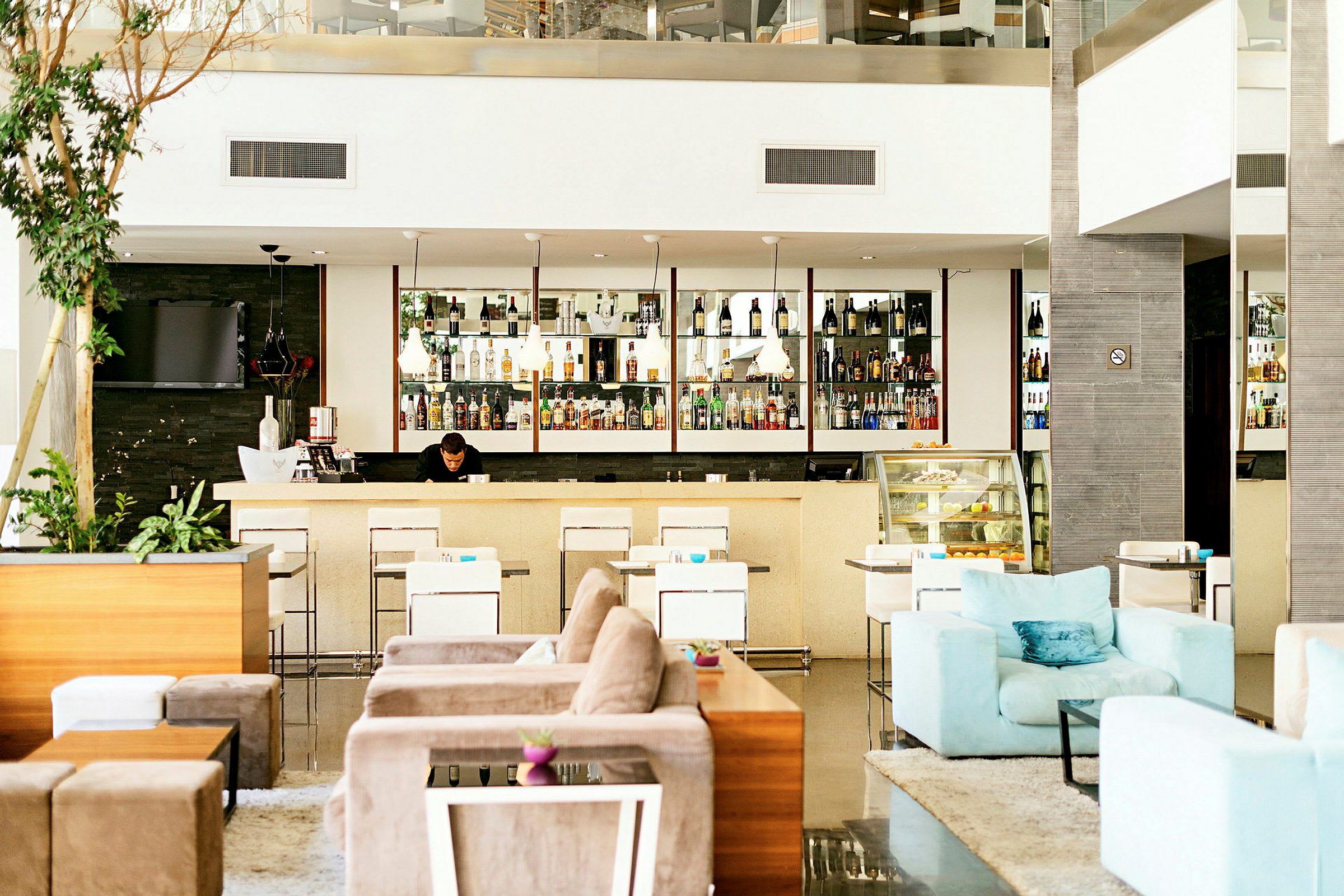 En hotellobby med en godt opplyst bar, moderne sittemøbler og en avslappet atmosfære. (AI-generert tekst)