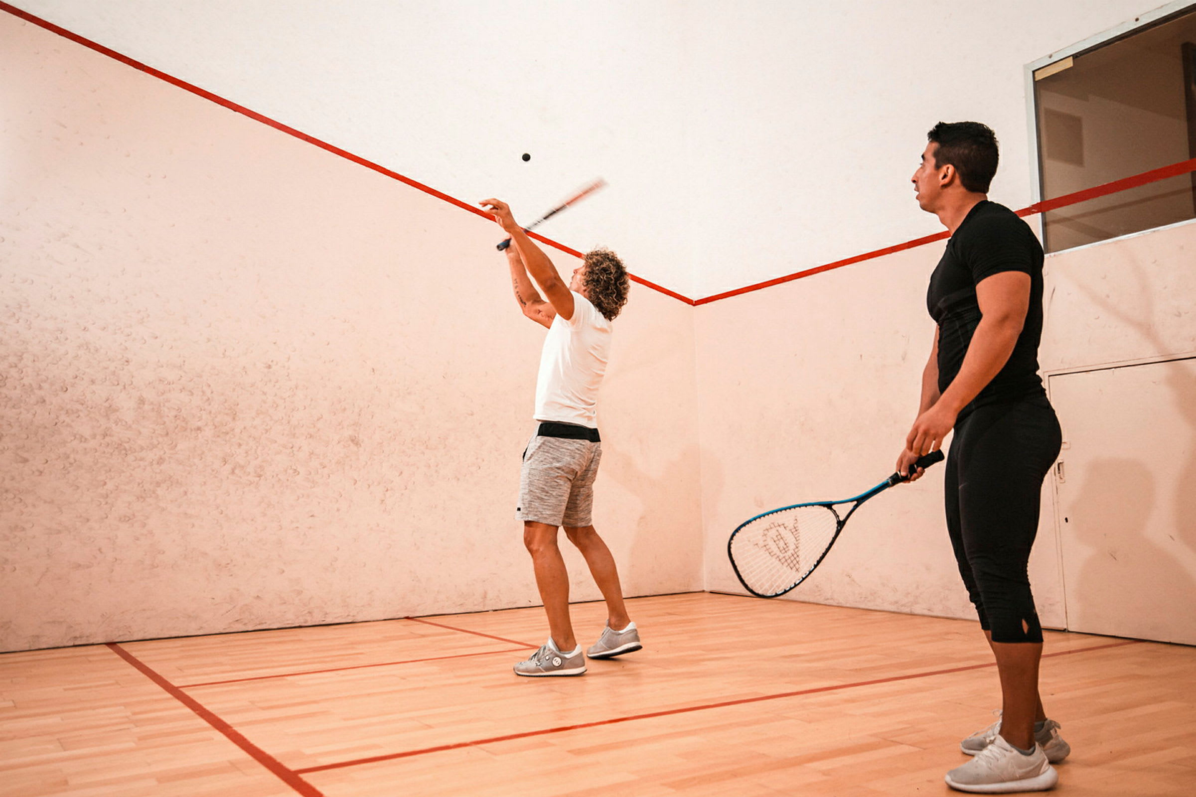 Personer spiller squash på en innendørsbane. (AI-generert tekst)