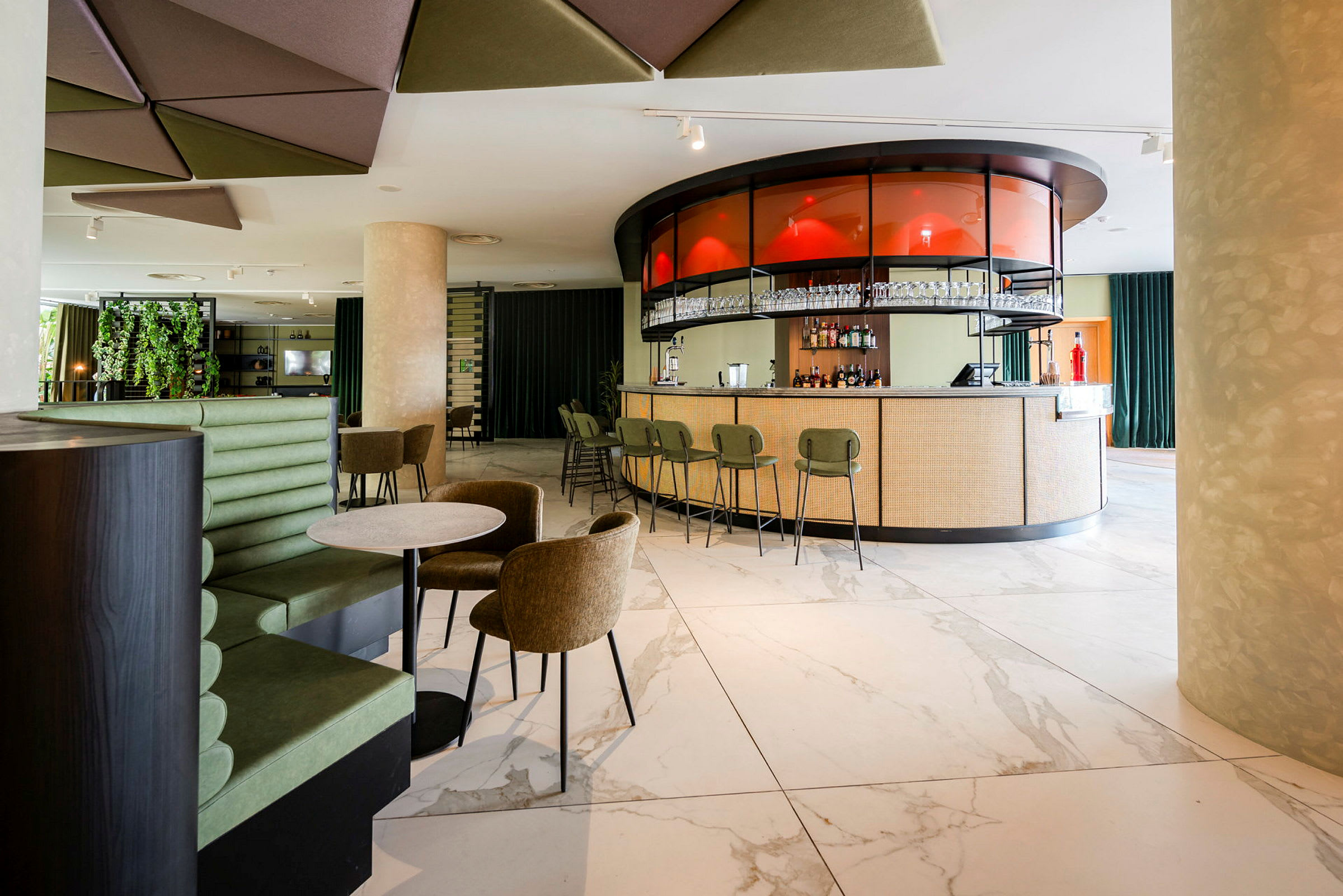 Interiør av en moderne bar med en rund bar og stoler, omkringliggende sitteplasser og dekorative detaljer. (AI-generert tekst)