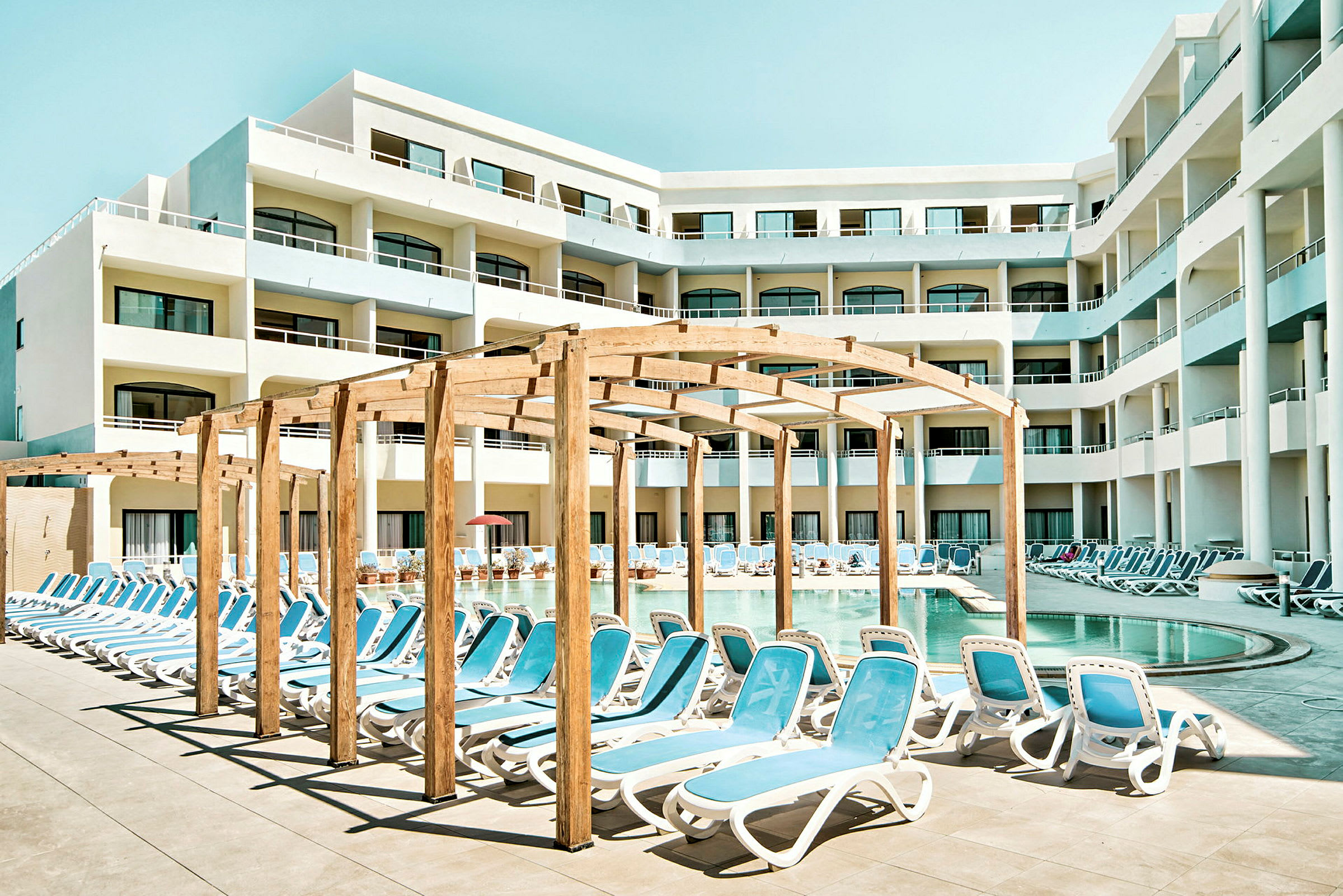 Bassengområde ved hotell med solsenger og skyggegivende pergola. (AI-generert tekst)