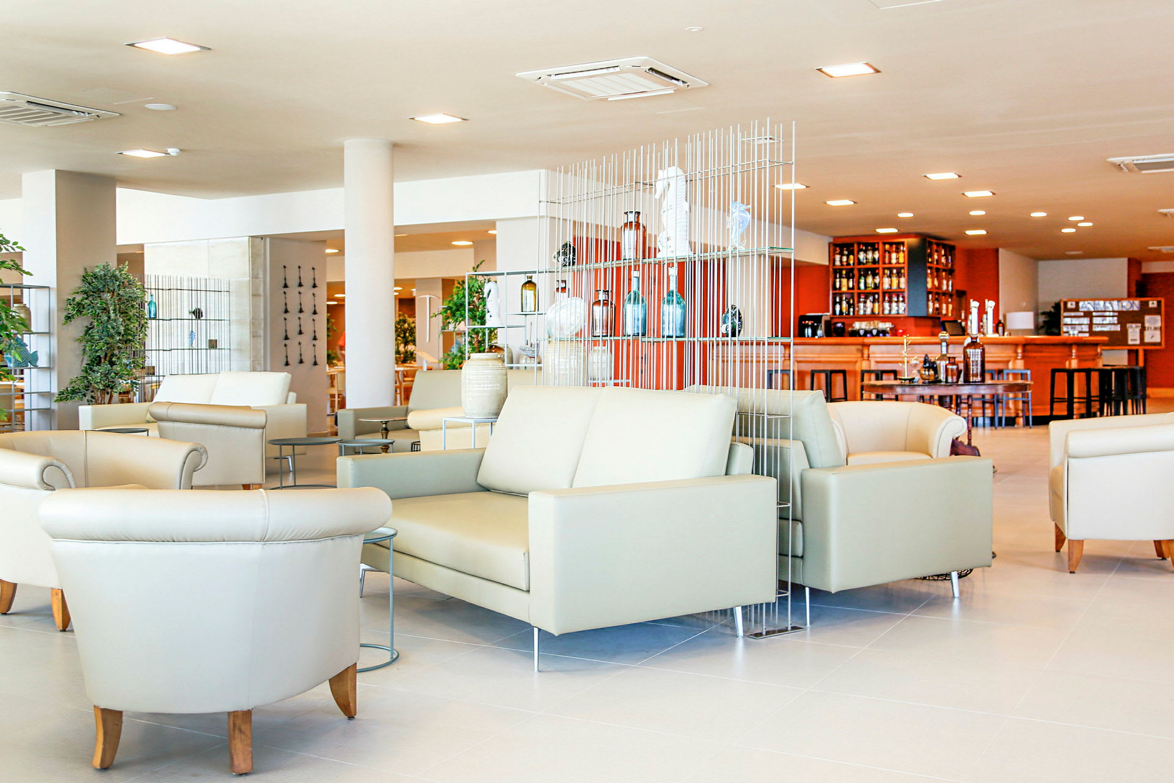 Lys og moderne lounge med sofaer og lenestoler samt en bar i bakgrunnen. (AI-generert tekst)