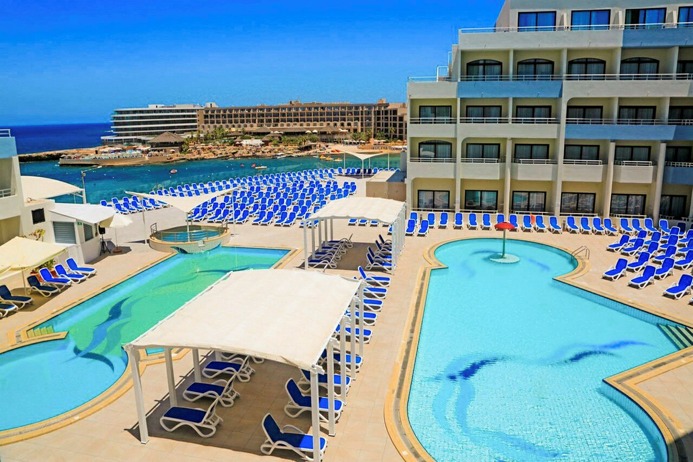 Et hotellbasseng med solsenger og havutsikt. (AI-generert tekst)
