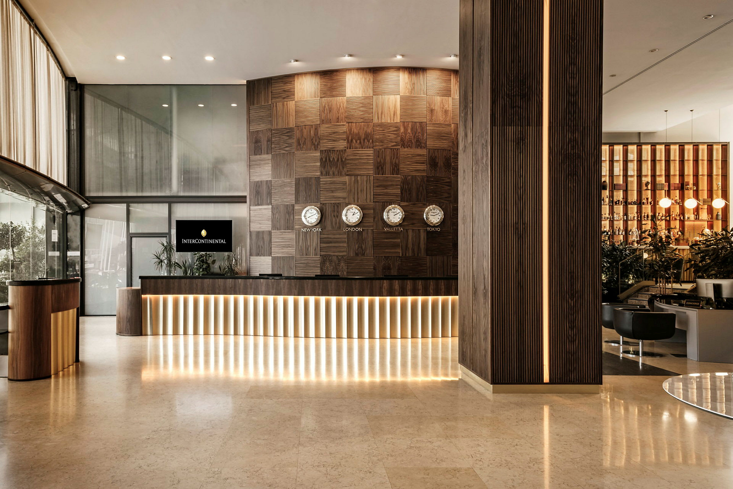 Resepsjonen på et hotell med moderne design, mørke trepaneler og flere klokker som viser forskjellige tidssoner. (AI-generert tekst)