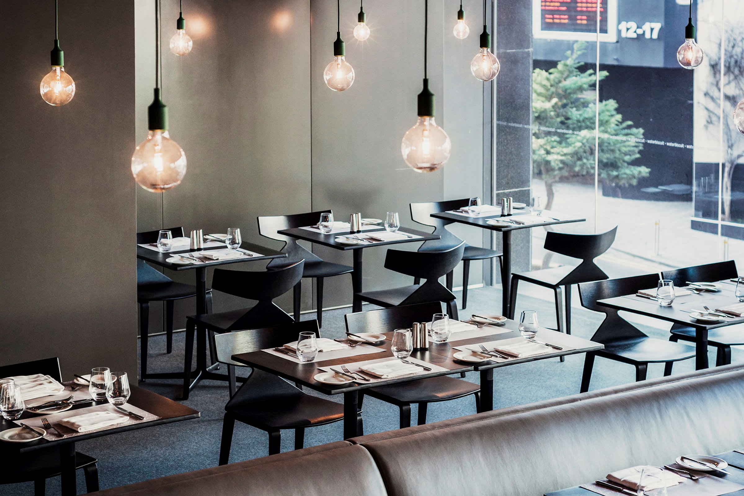 En moderne restaurant med elegant dekkede bord og hengende lyspærer. (AI-generert tekst)