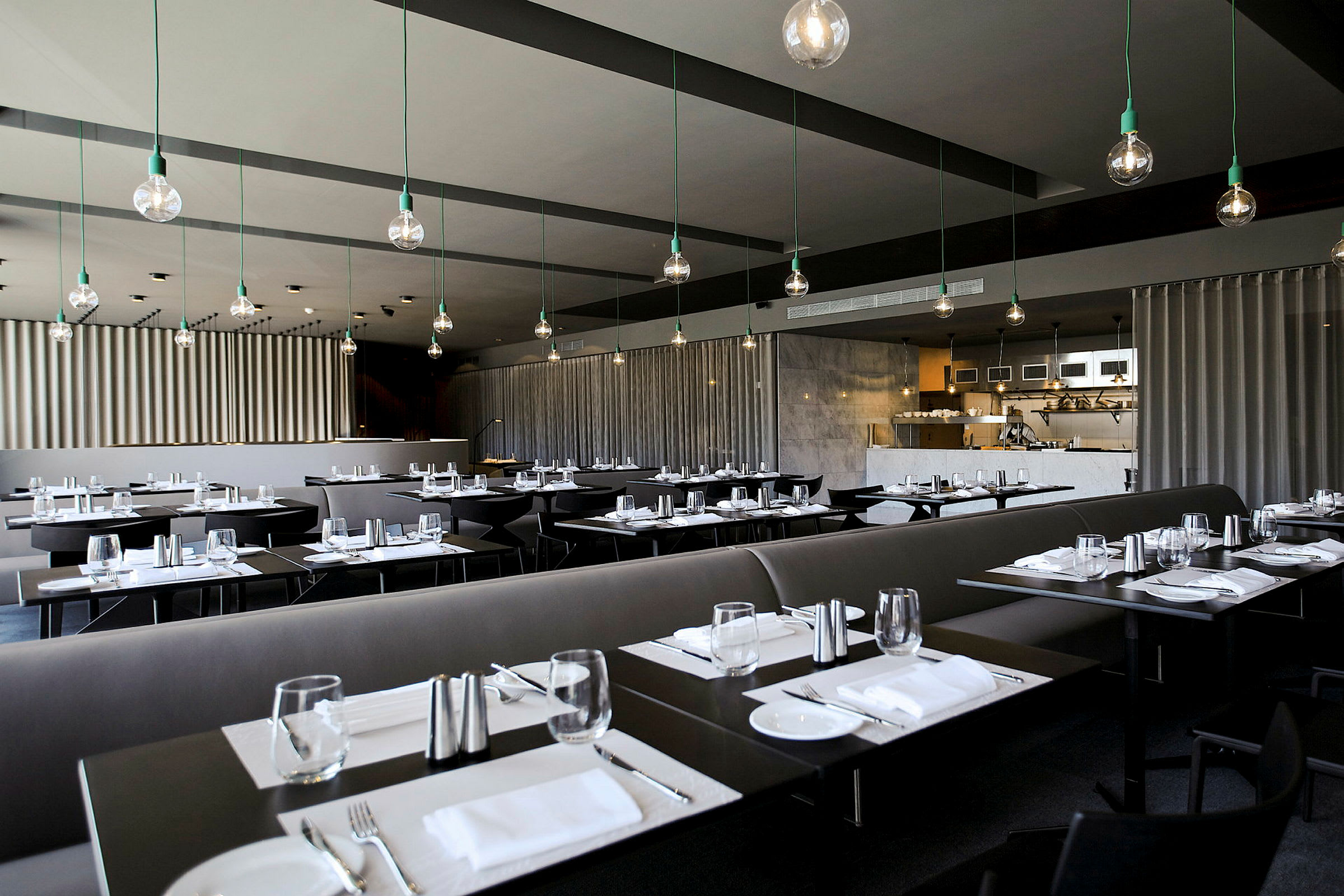 En moderne restaurant med mørke bord, dekket for måltid og stilfull takbelysning. (AI-generert tekst)