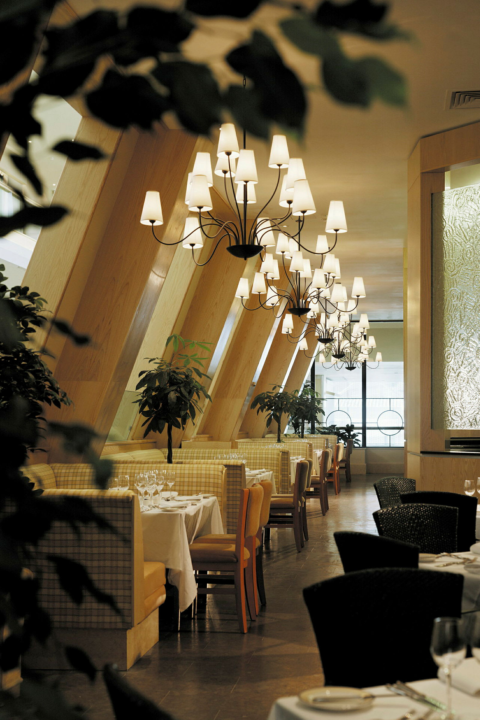 Bilde av en elegant restaurant med dekkede bord, lysekroner og grønne planter. (AI-generert tekst)