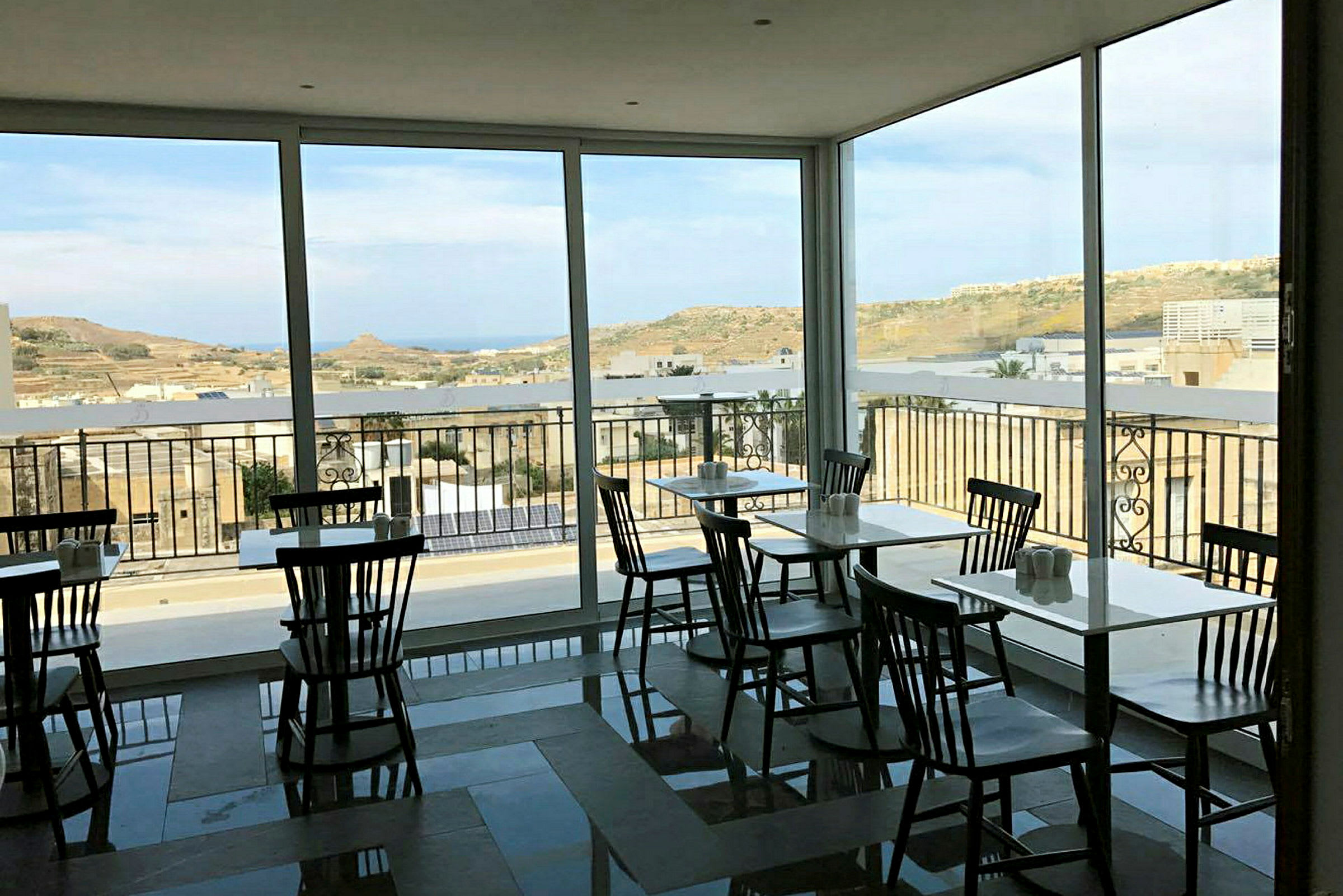 En kafé med store vinduer og utsikt over et landskap. (AI-generert tekst)