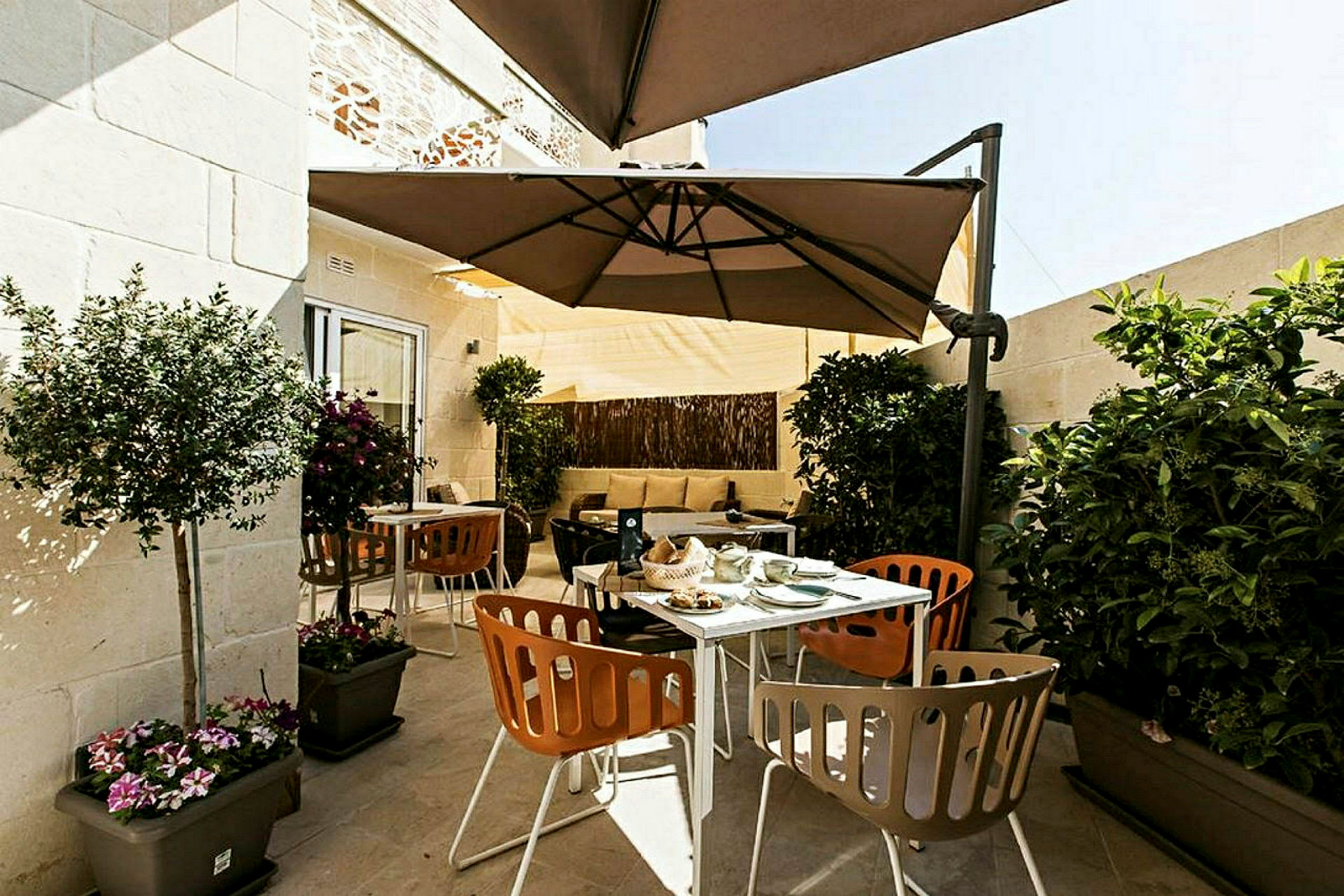 En terrasse med utemøbler, parasoll og planter. (AI-generert tekst)