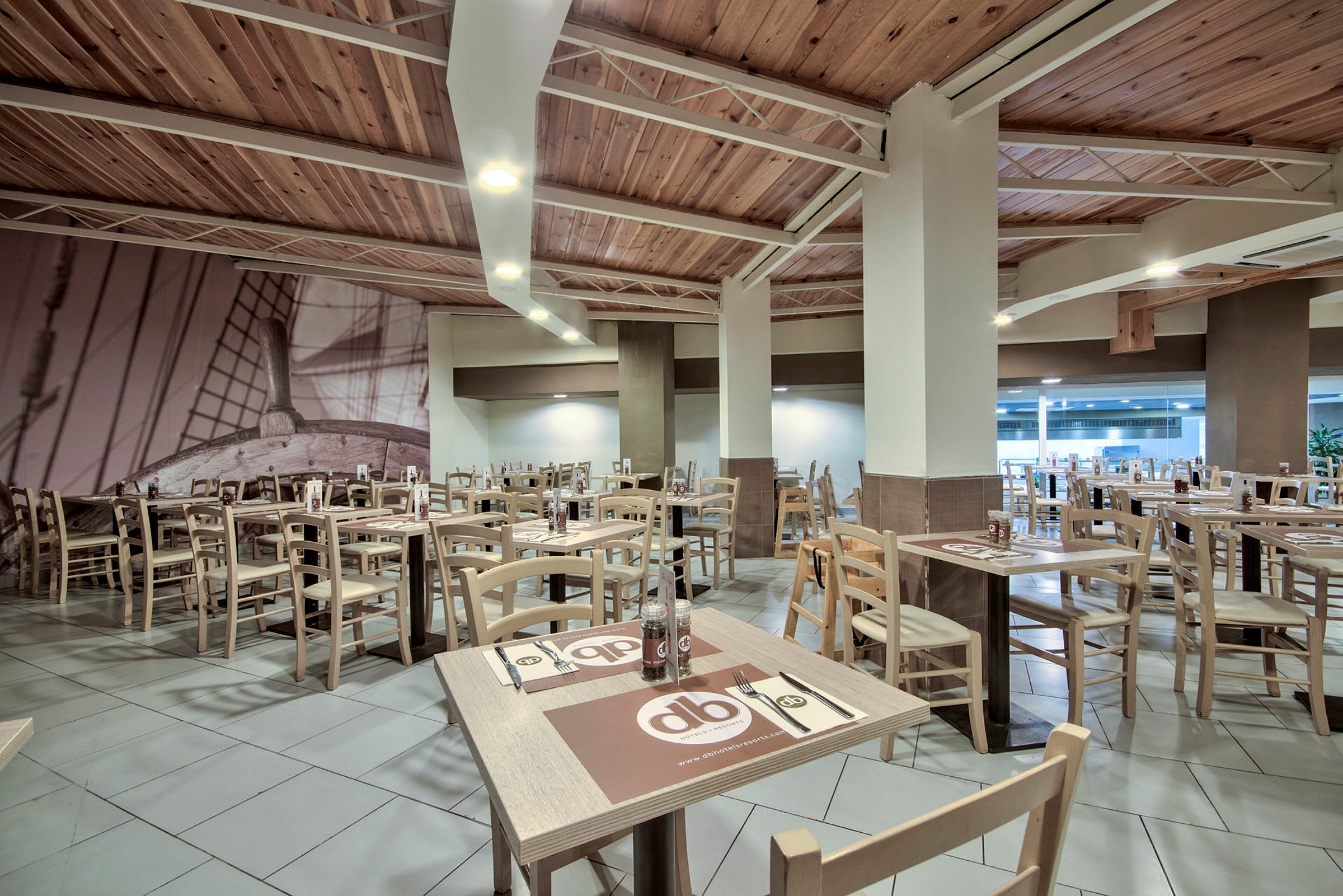 Restaurant med trebord og stoler samt væggdekorasjon av et skip. (AI-generert tekst)