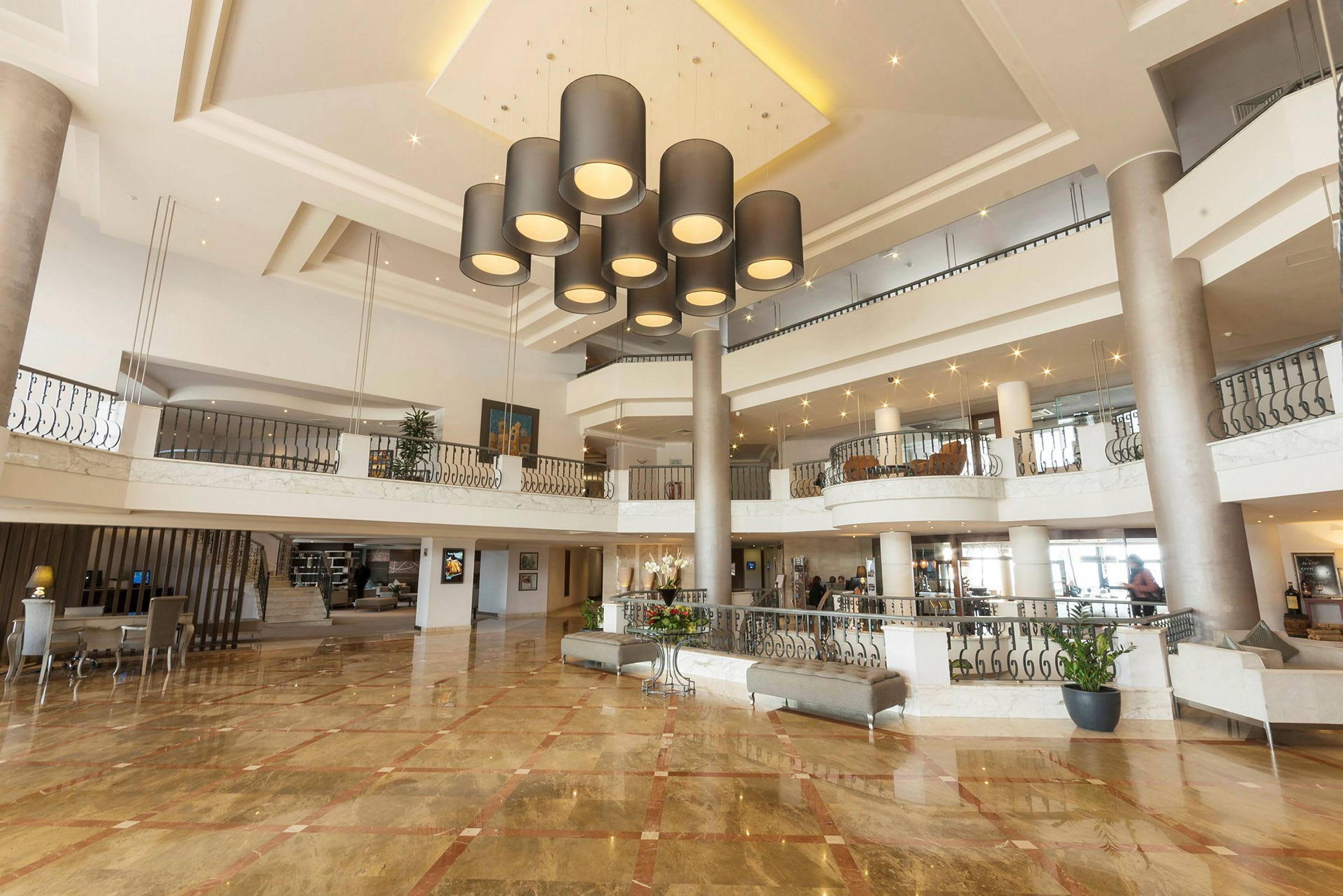 Et hotellobbyområde med elegante lysarmaturer i taket, marmorgulv og moderne innredning. (AI-generert tekst)