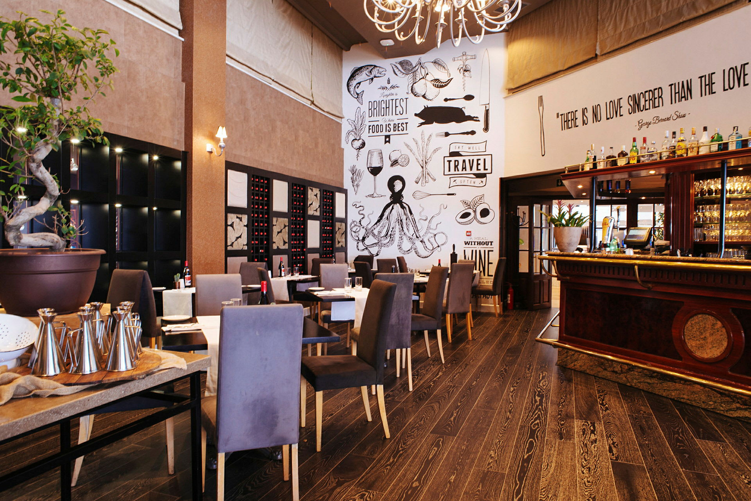 En hyggelig restaurant med sitteplasser, en dekorativ vegg med tekster og tegninger, samt en bar til høyre. (AI-generert tekst)