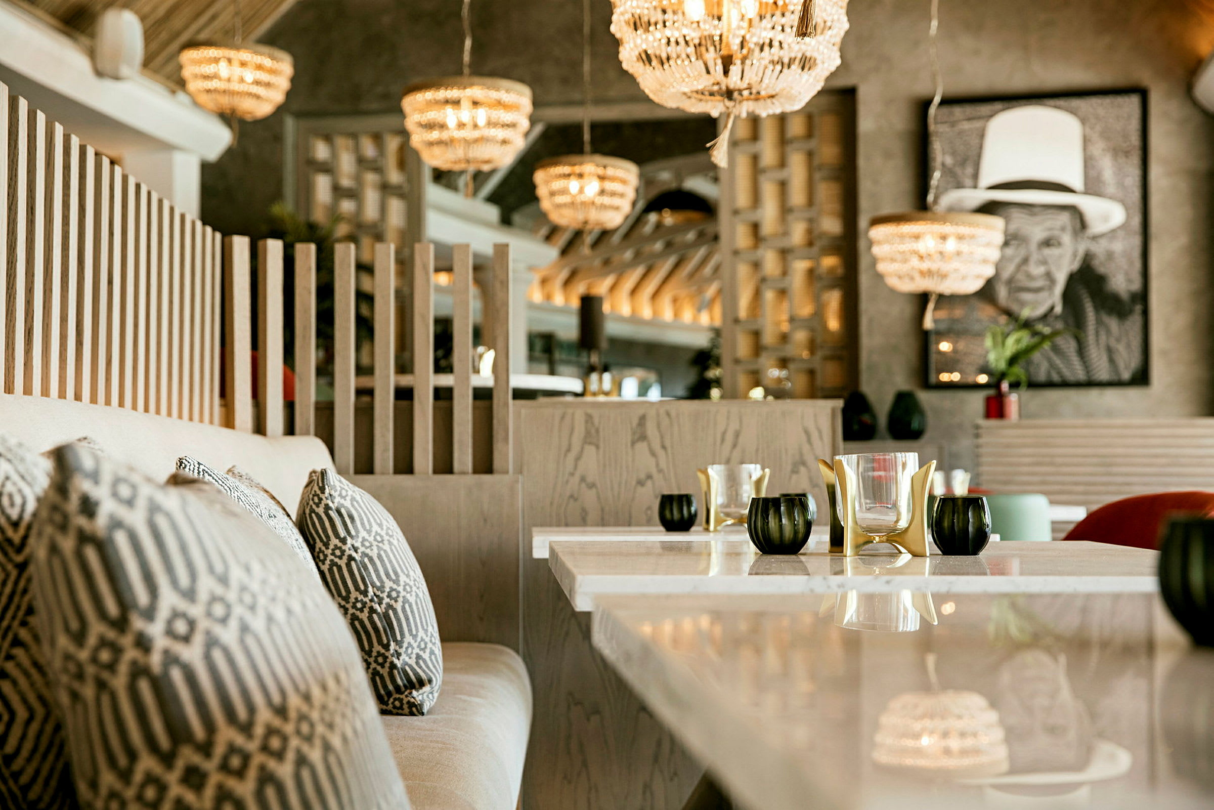En elegant restaurant med sofaer, puter, lyslykter og store lysekroner i taket. (AI-generert tekst)
