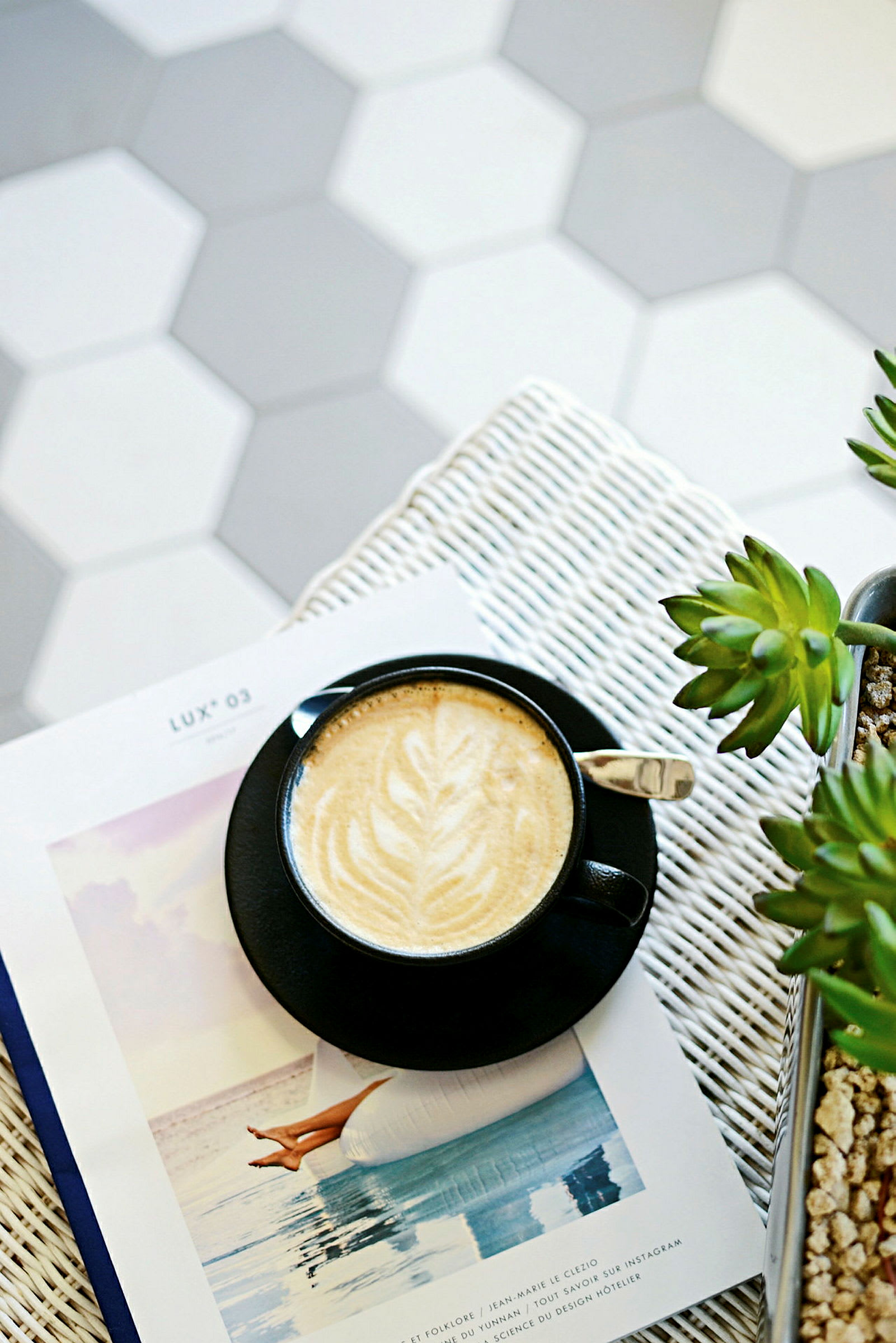 En kopp kaffe med latte art står på en bok ved siden av planten. (AI-generert tekst)