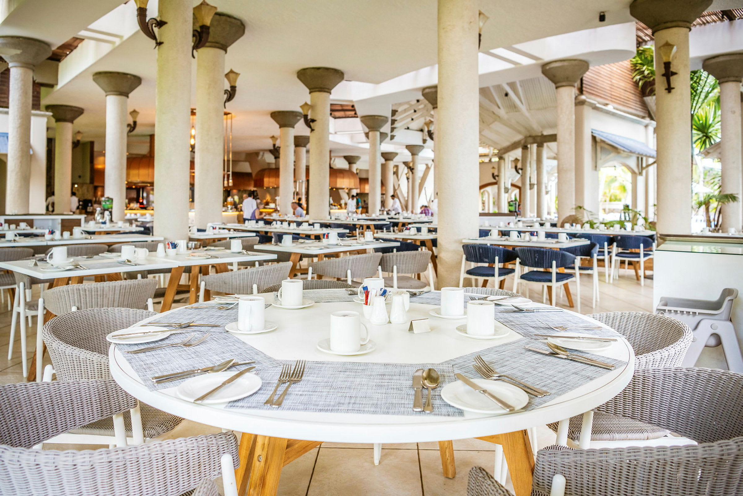 Et luftig restaurantområde med runde bord, stoler og dekkede plasser. (AI-generert tekst)