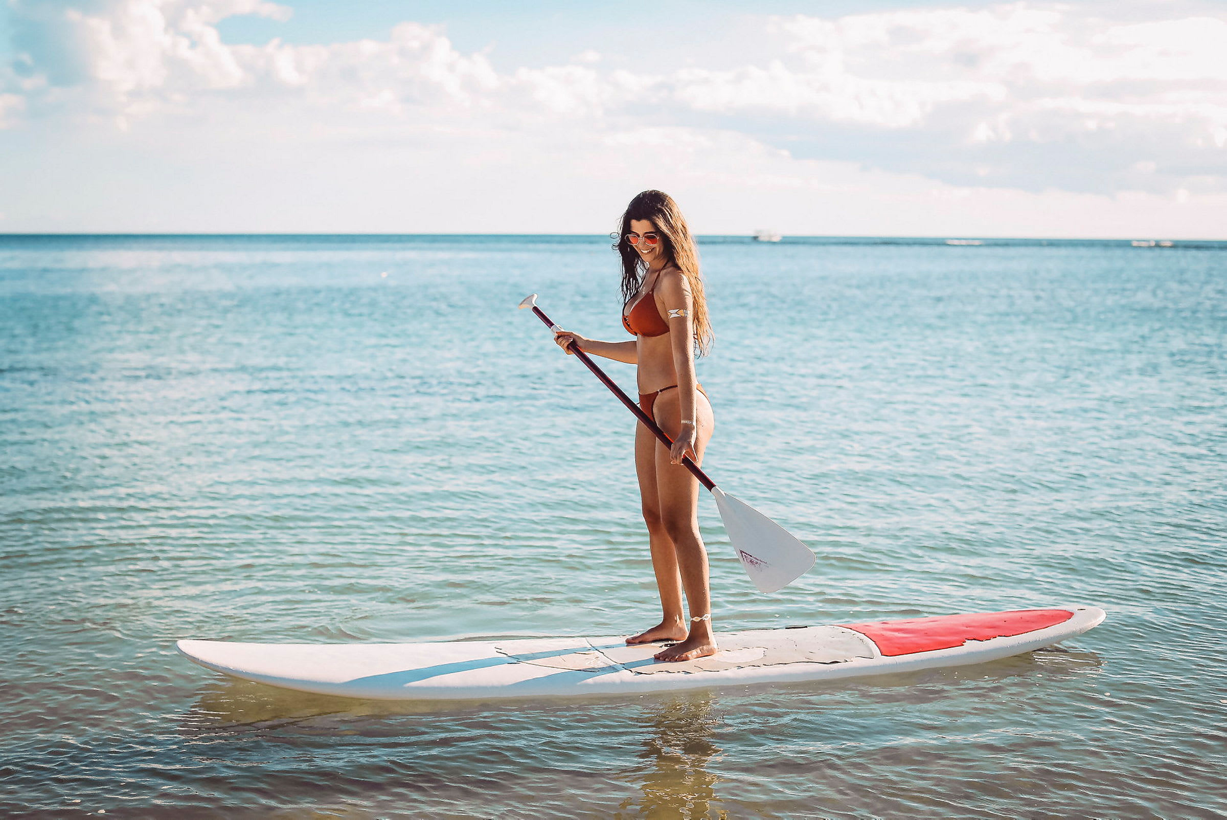 Person står på et paddleboard i vannet. (AI-generert tekst)