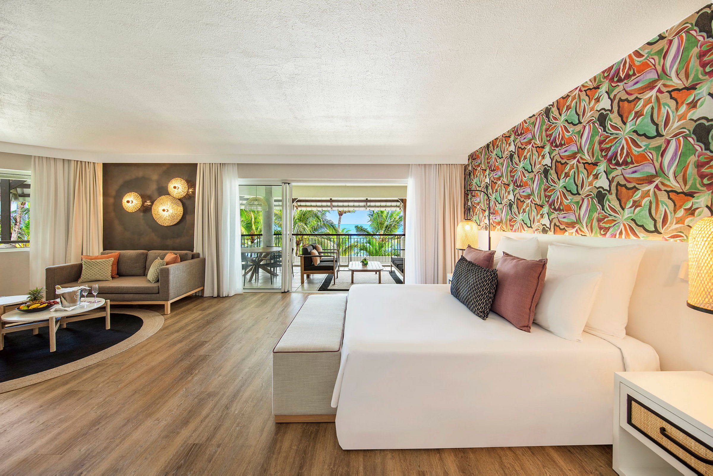 Et elegant hotellrom med en dobbeltseng, en sittegruppe og en balkong med utsikt over tropiske palmer. (AI-generert tekst)