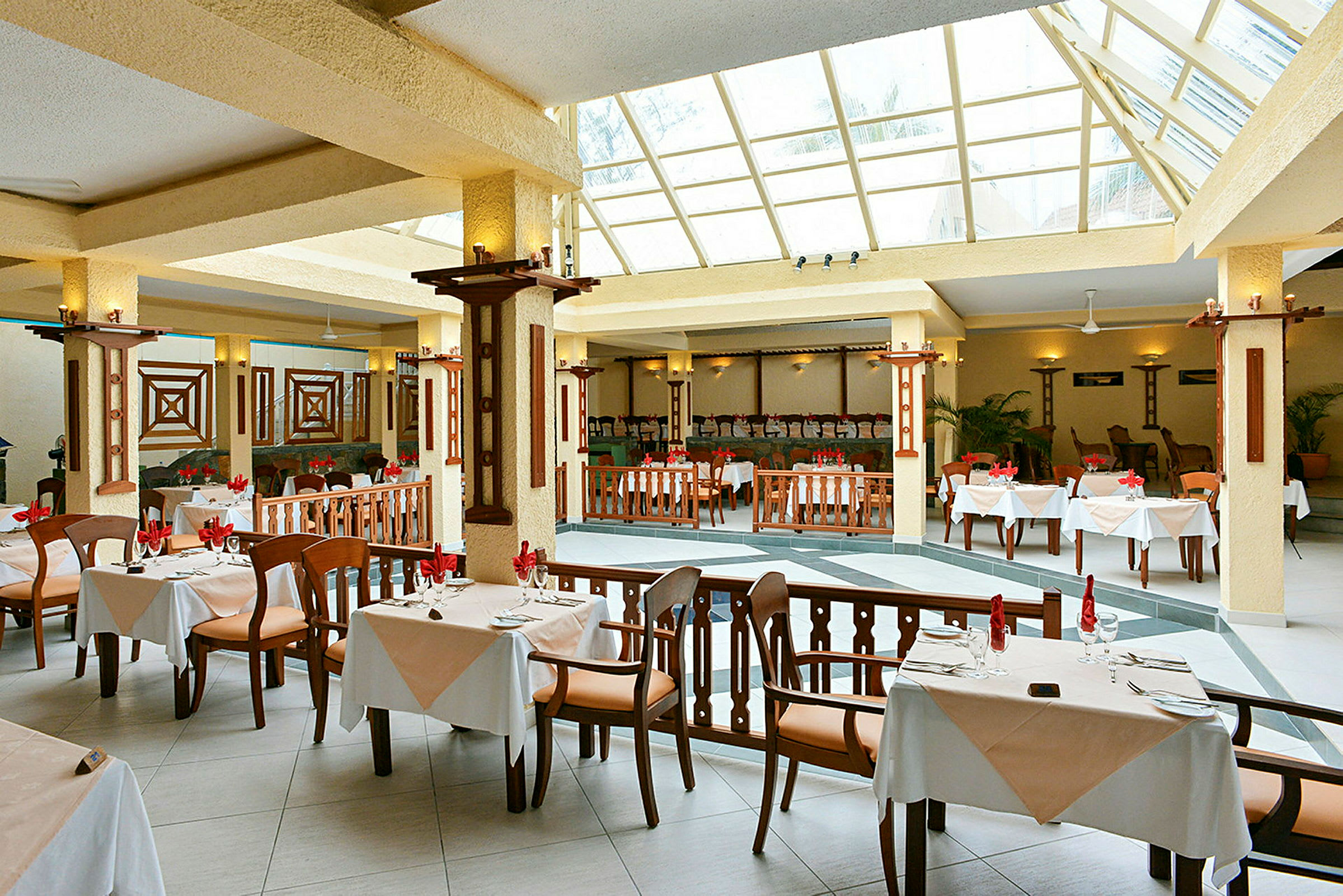 En romslig restaurant med store vinduer og bord med hvitduker. (AI-generert tekst)