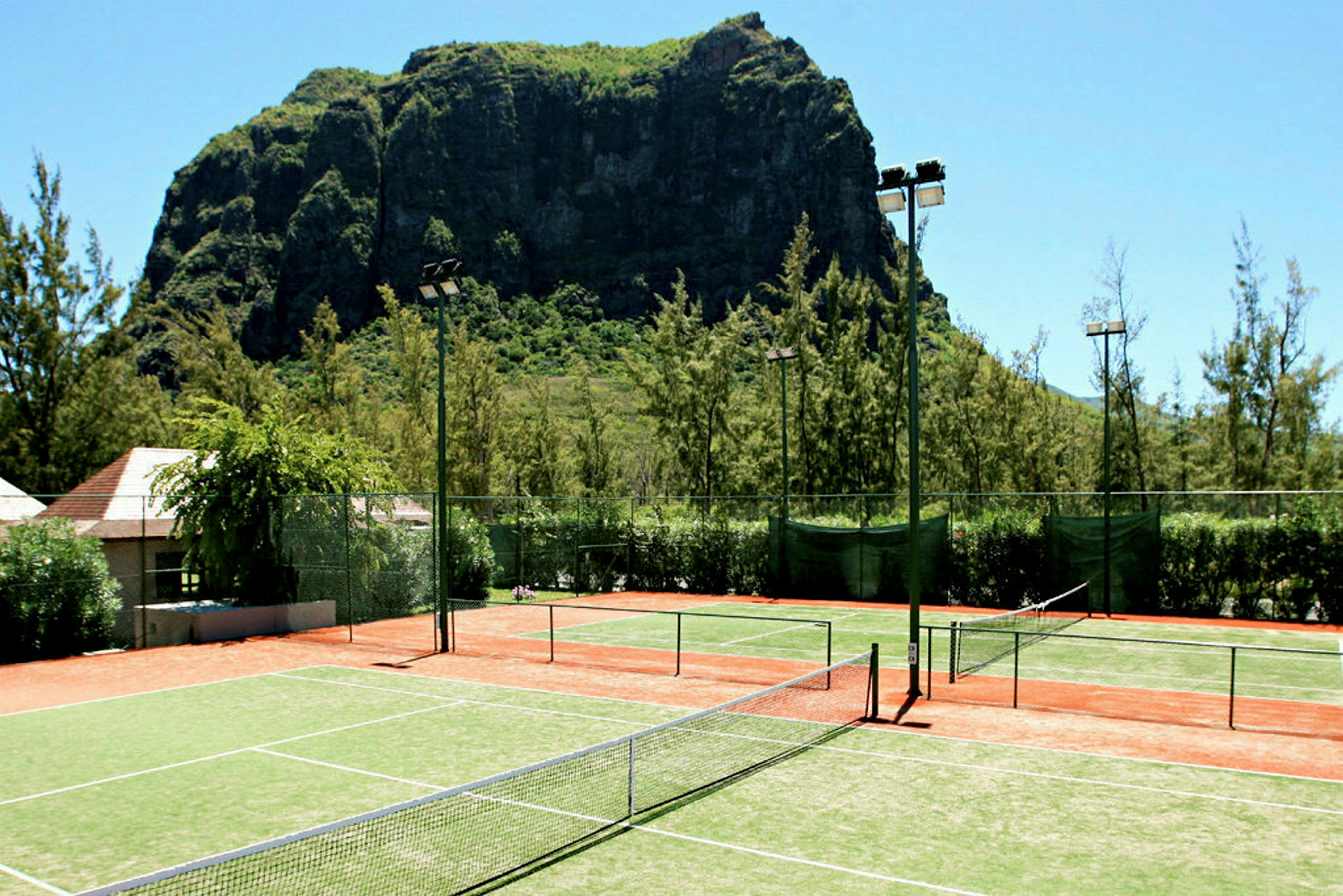 Tennisbaner foran en stor klippe. (AI-generert tekst)