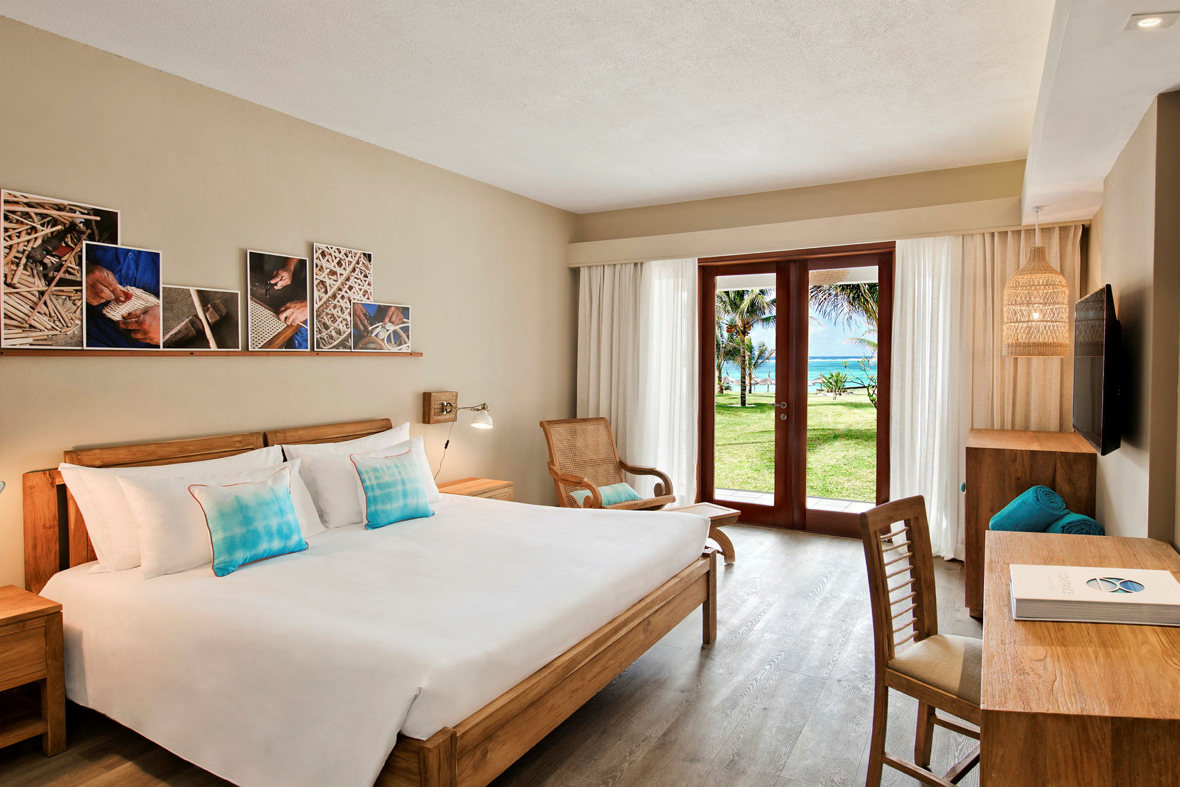 Et hotellrom med en dobbeltseng, tremøbler, og en glassdør som åpner opp til en grønn hage og havutsikt. (AI-generert tekst)