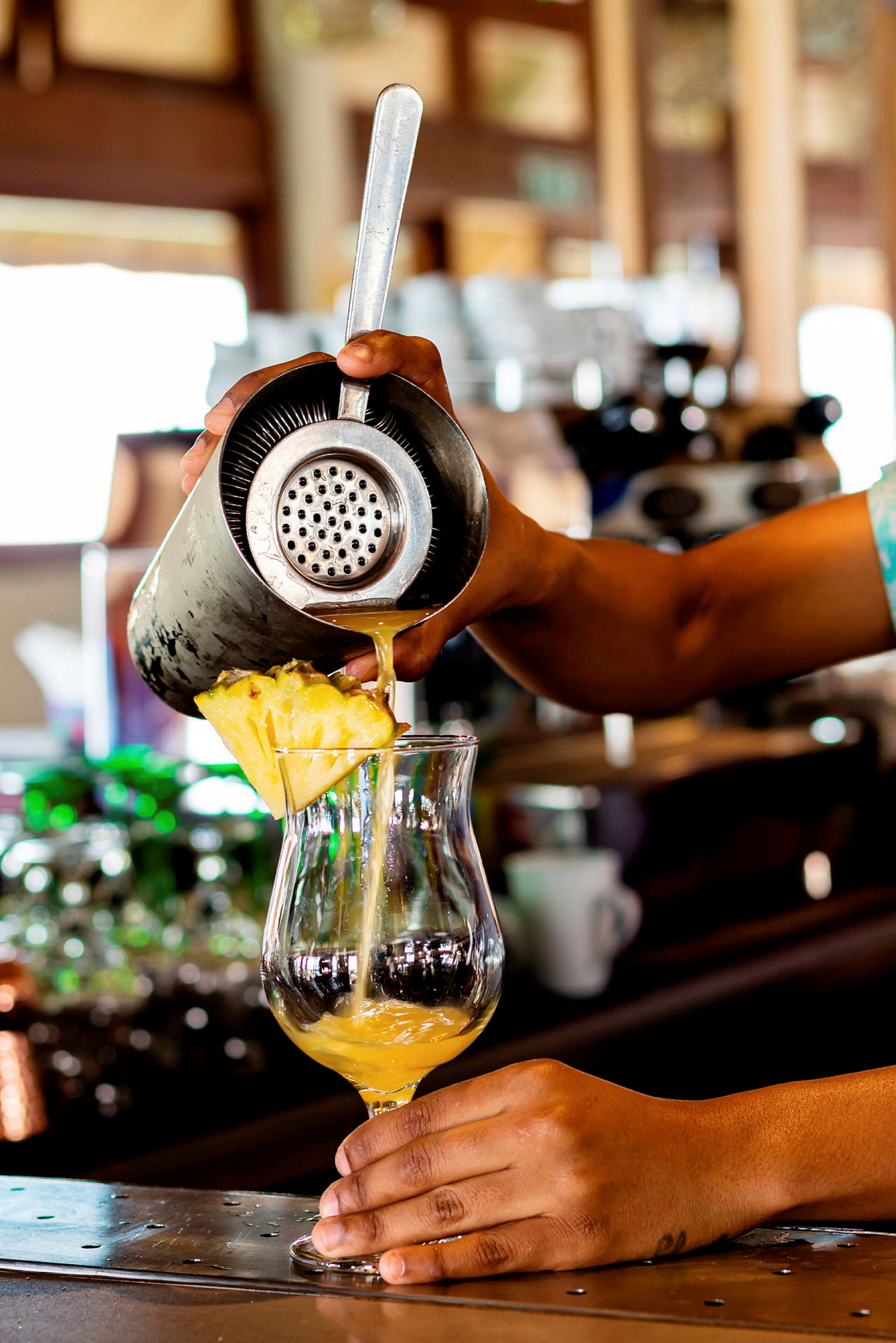 En drink helles opp i et glass på en bardisk. (AI-generert tekst)