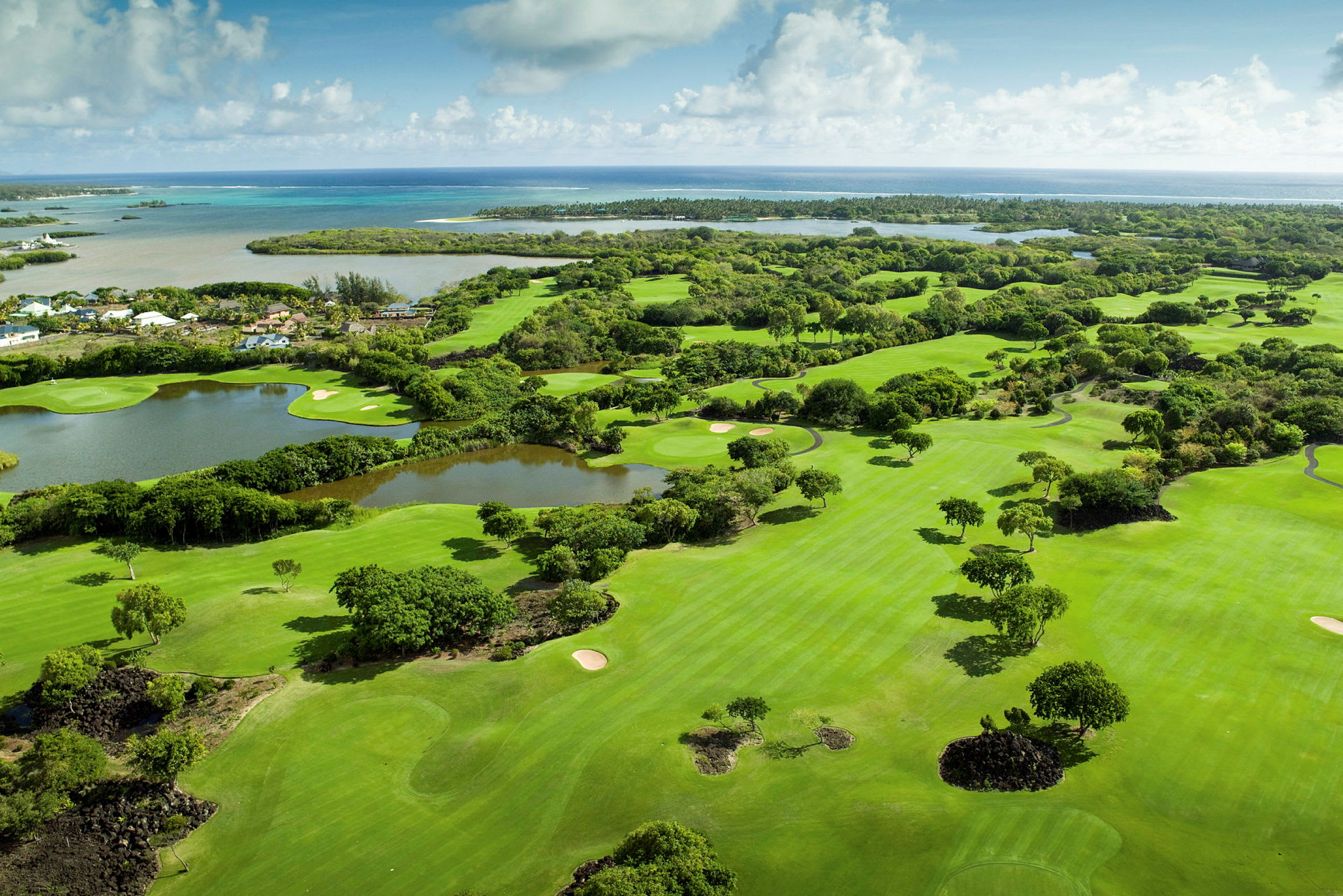Flyfoto av en golfbane omgitt av grøntområder med havet i bakgrunnen. (AI-generert tekst)