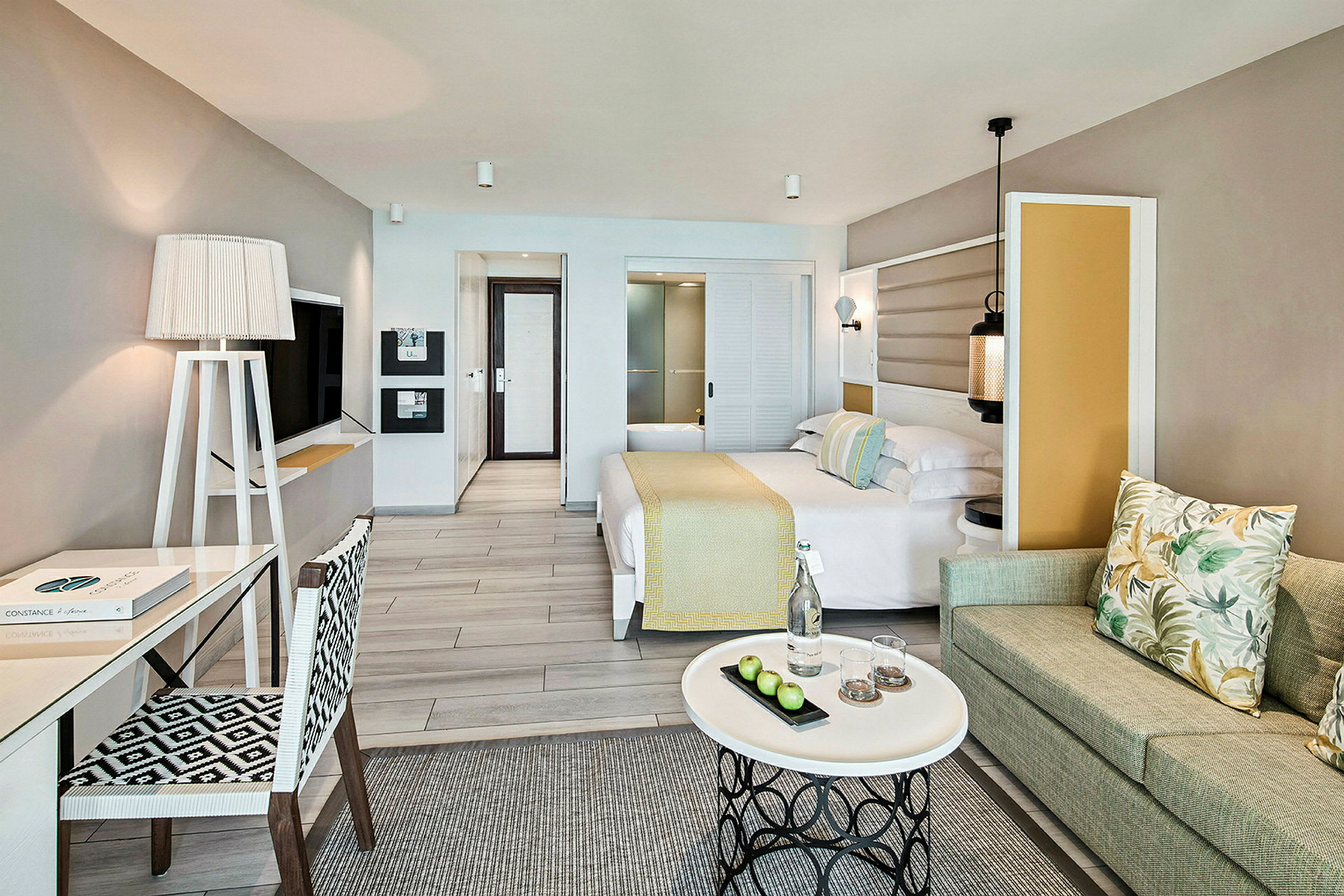 Et hotellrom med moderne innredning, seng, skrivebord, sofa og et kaffebord. (AI-generert tekst)