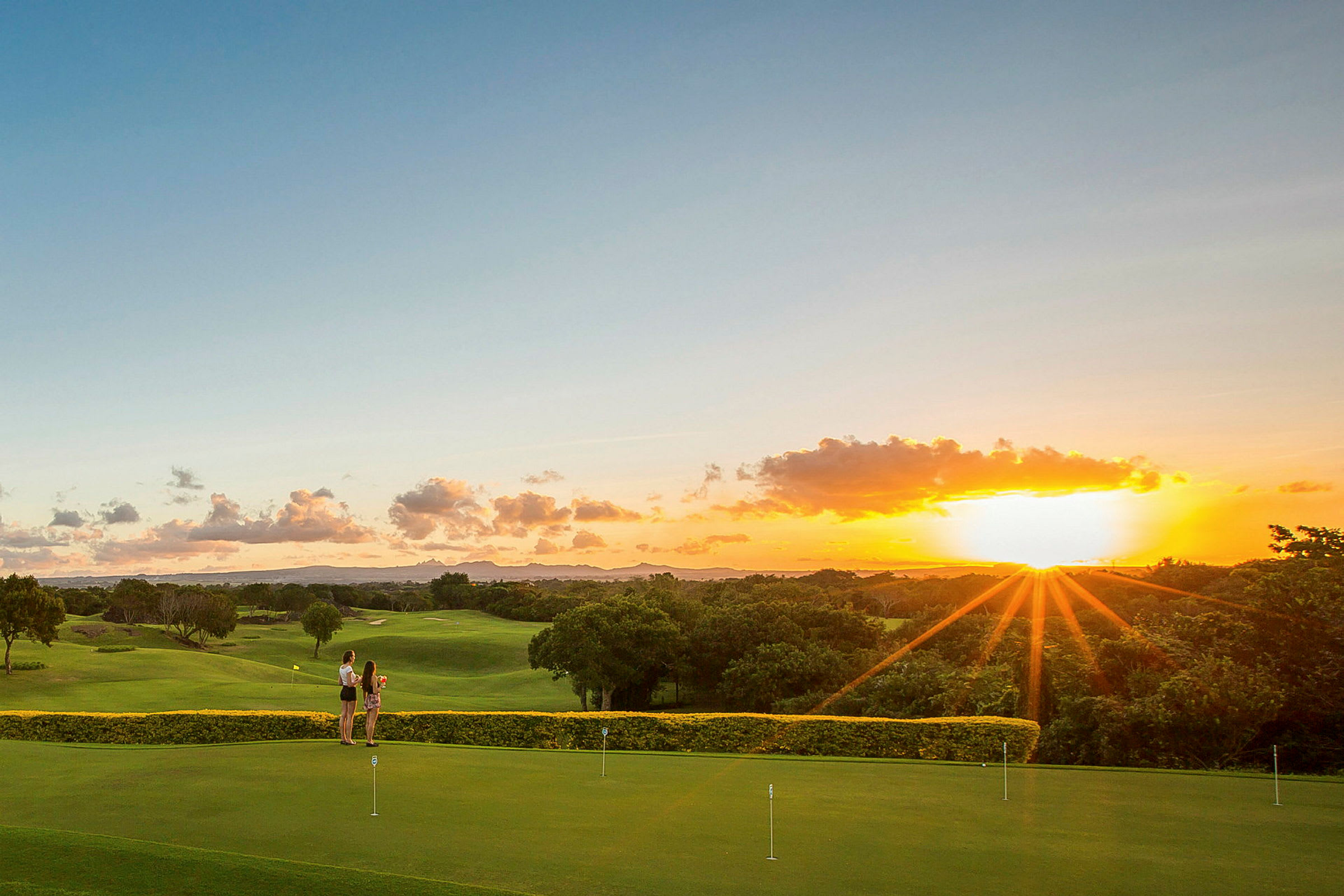 To personer står på en golfbane ved solnedgang. (AI-generert tekst)