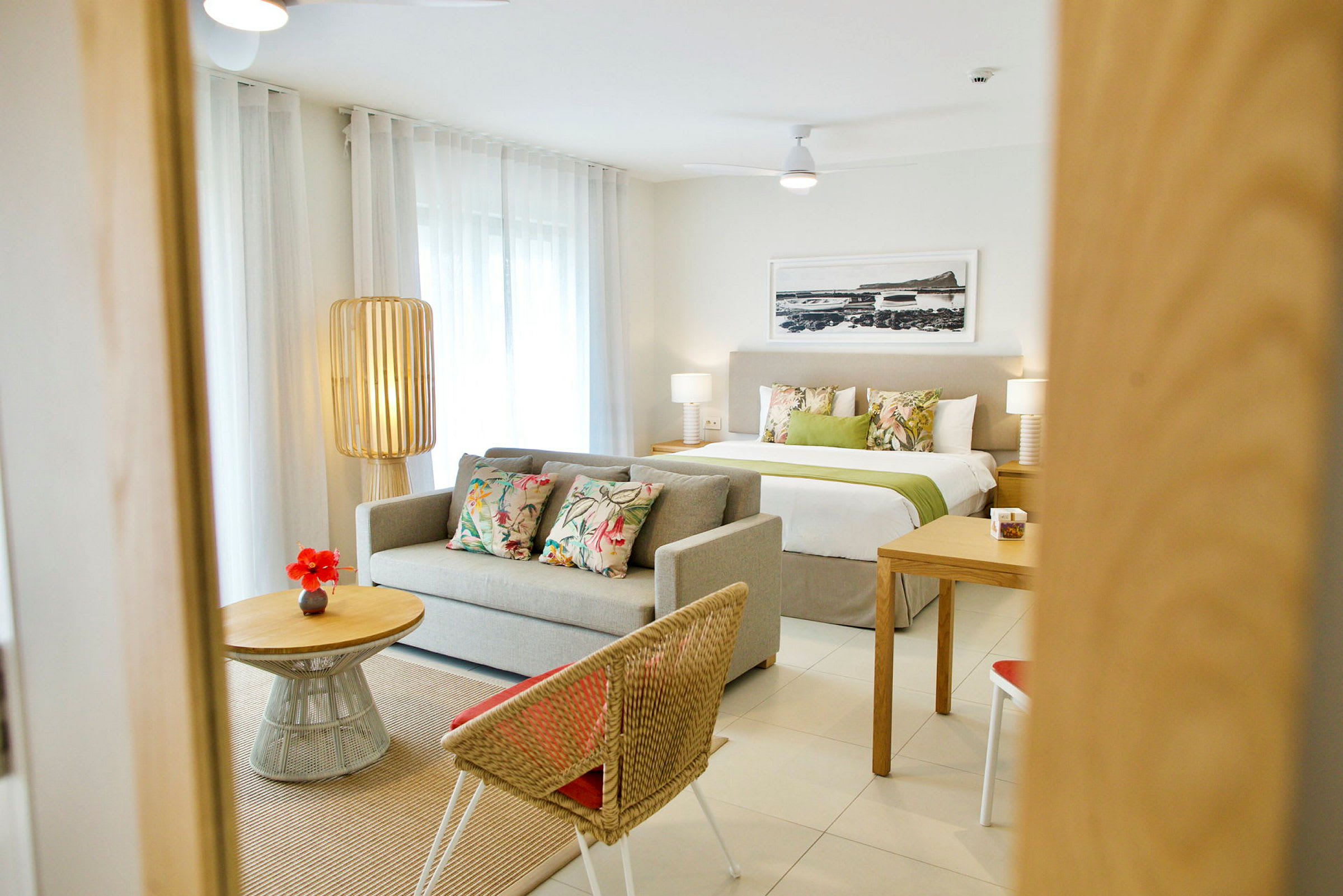 Et moderne innredet hotellrom med sofa, seng og bord. (AI-generert tekst)