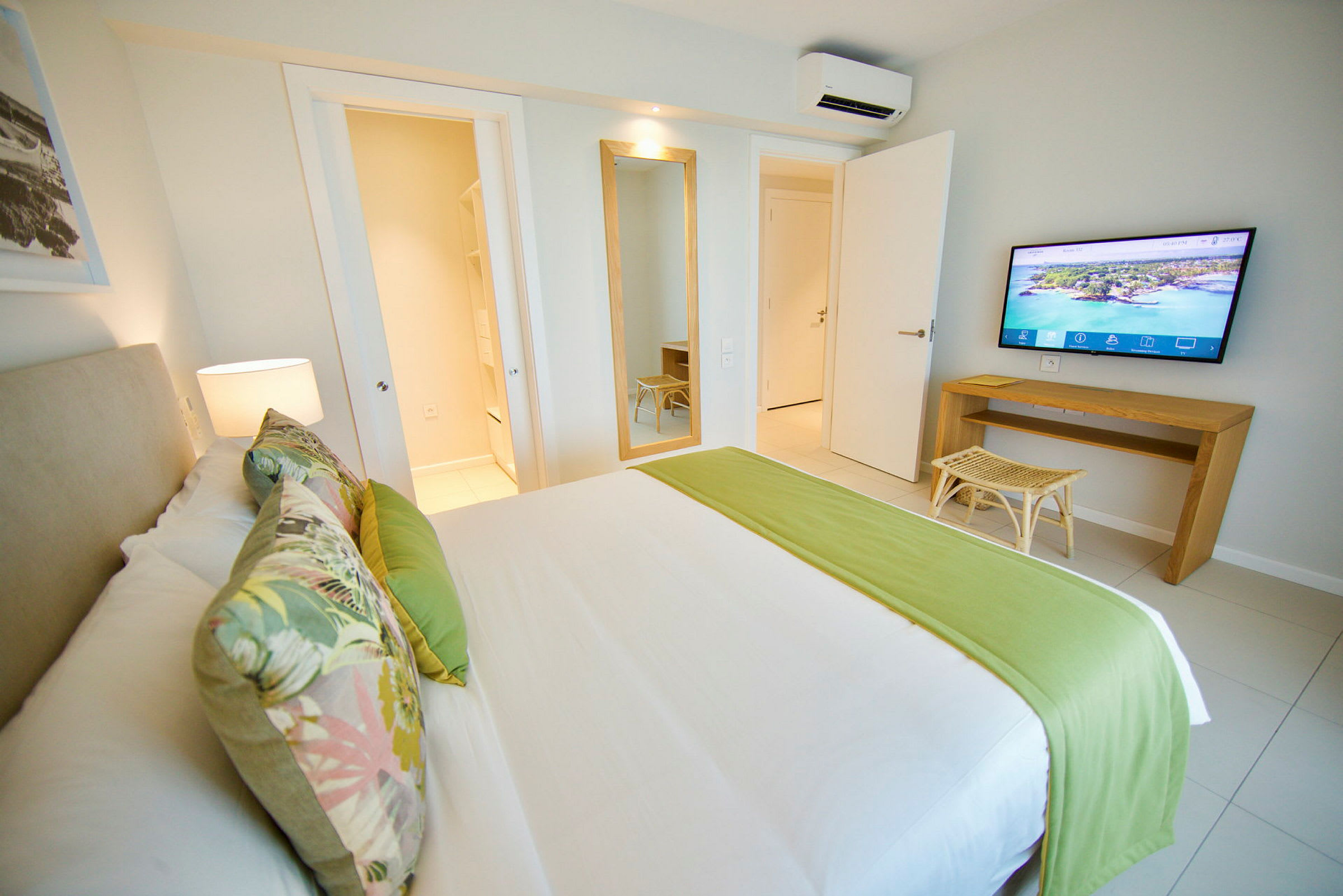 Et hotellrom med en seng, veggspeil og TV. (AI-generert tekst)