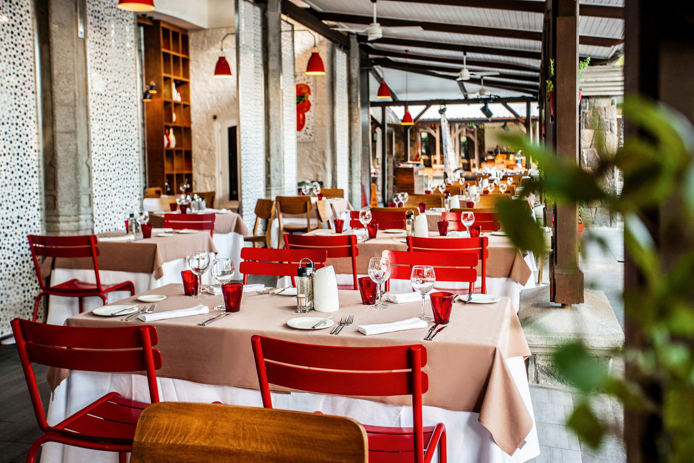 Restaurant med dekte bord og røde stoler. (AI-generert tekst)