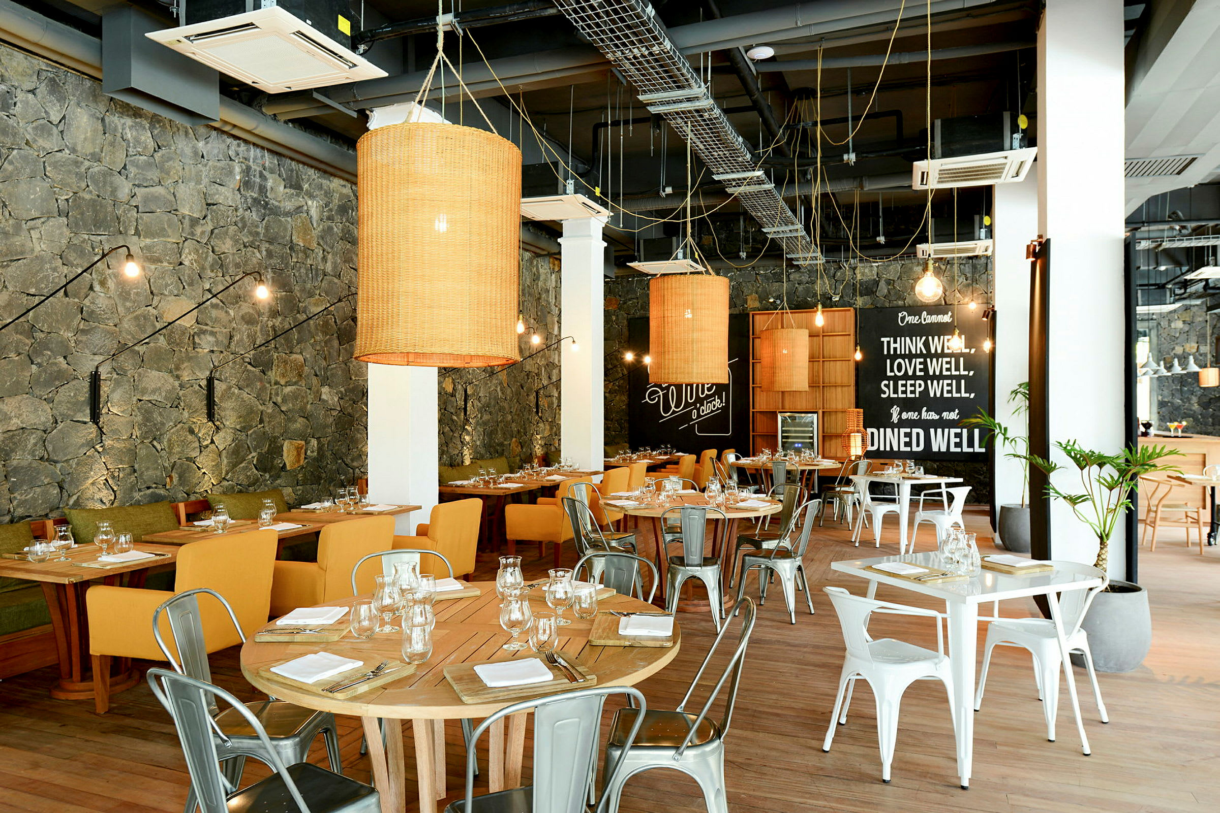 En innendørs restaurant med trebord og stoler, dekorert med vegglamper og store lykter. (AI-generert tekst)