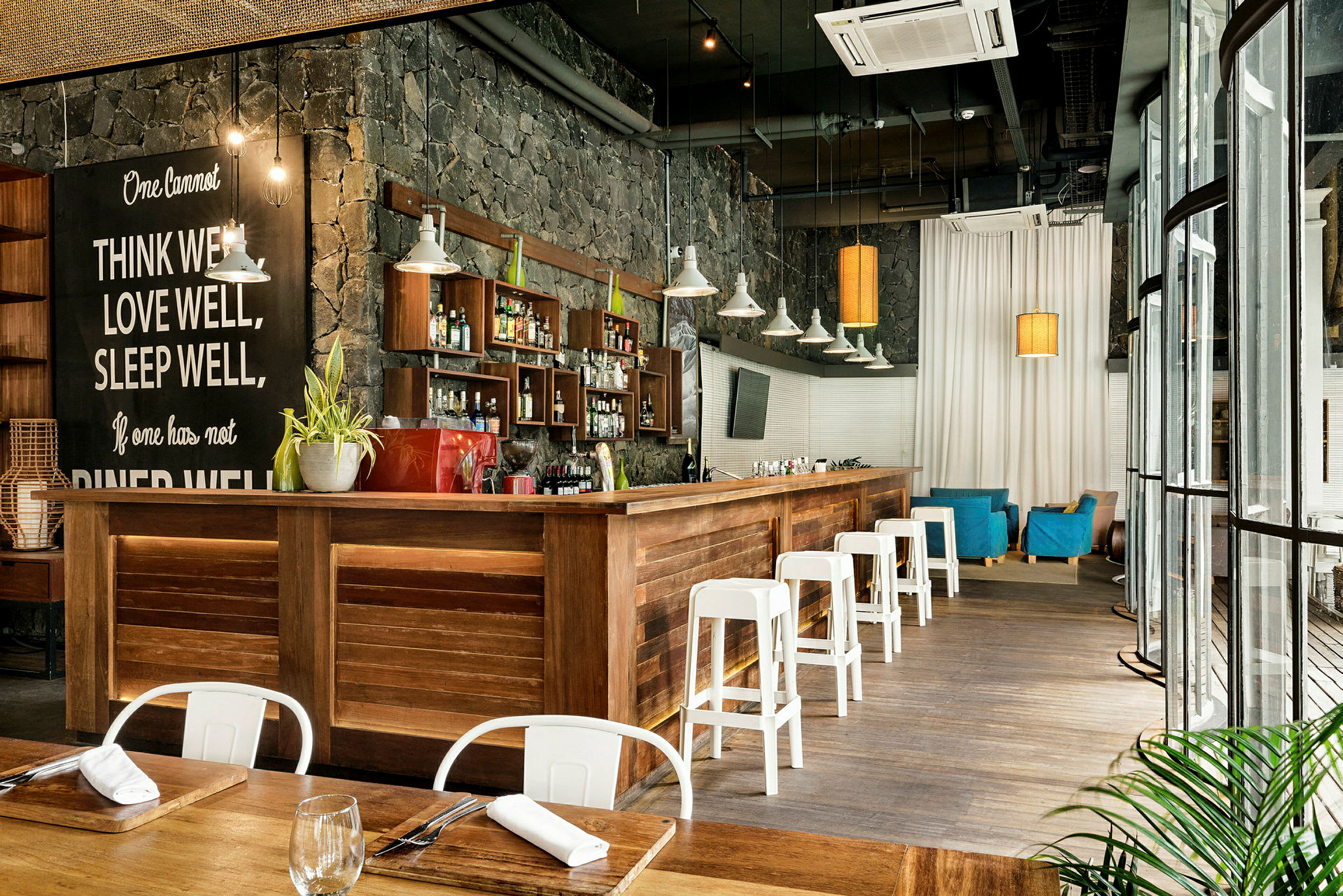 En interiør av en moderne bar med treinteriør, hvite stoler og en steinvegg. (AI-generert tekst)