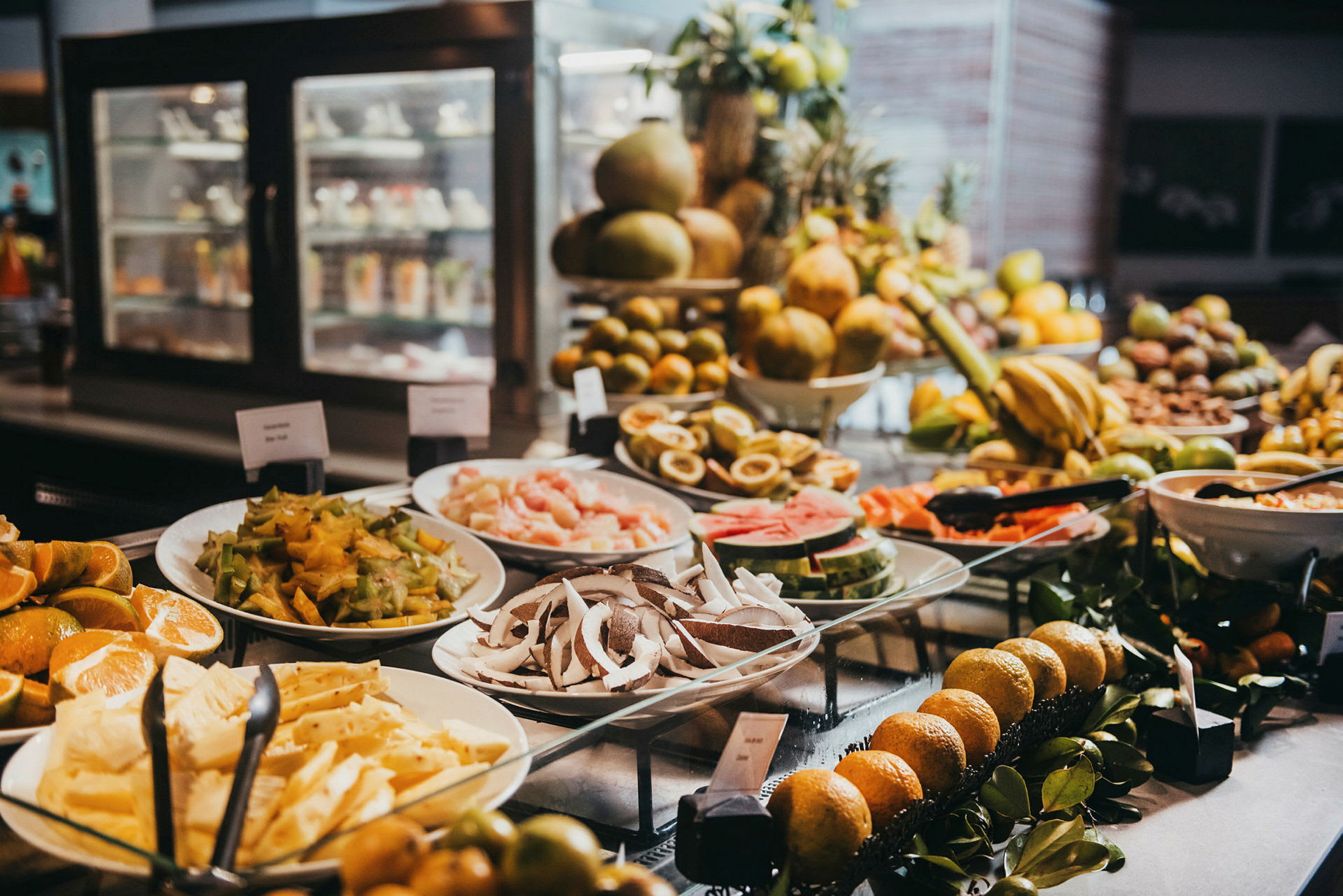 Et buffetbord med forskjellige tropiske frukter og skiver lagt opp på tallerkener. (AI-generert tekst)