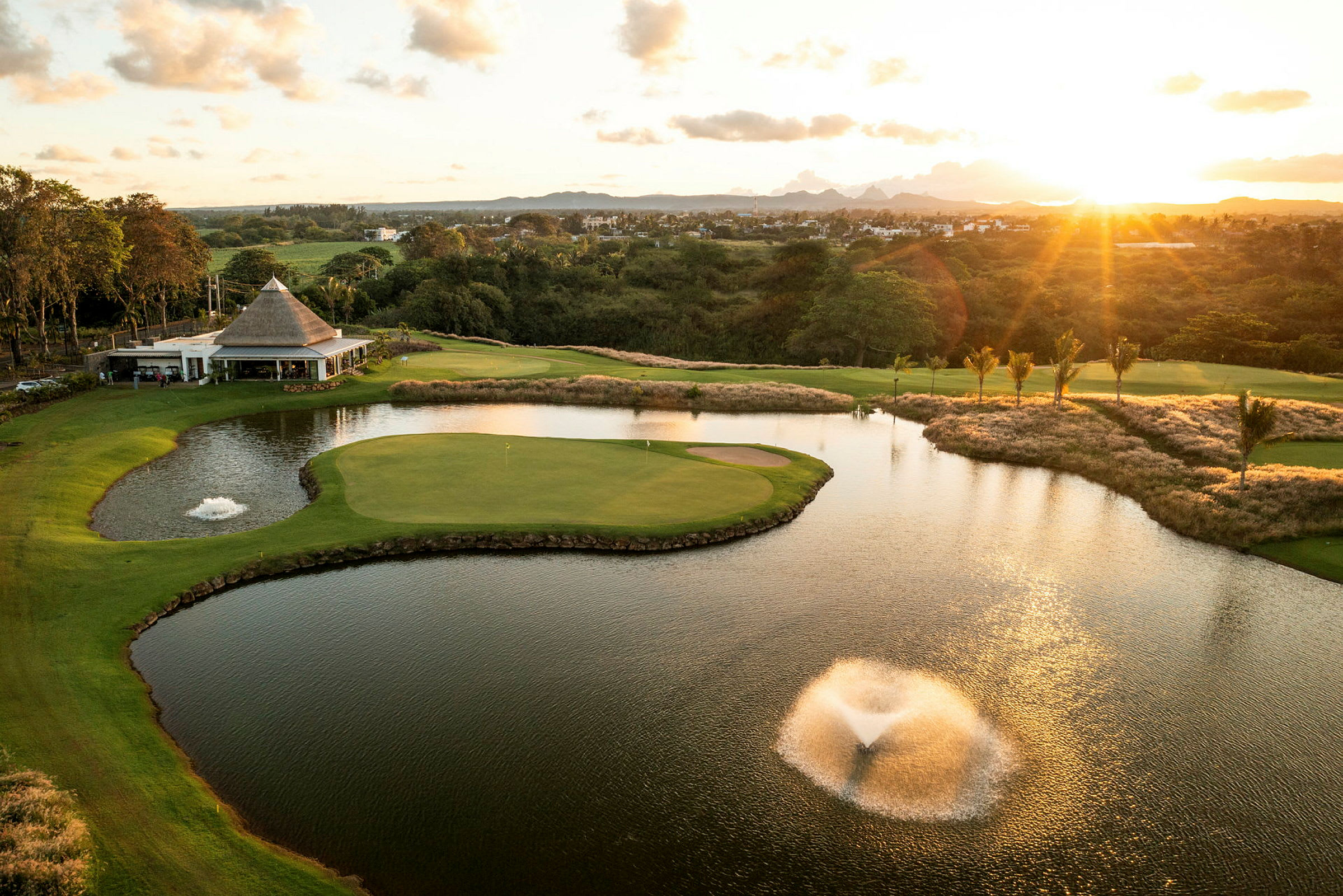 Golfbane med en dam og fontene under solnedgangen. (AI-generert tekst)