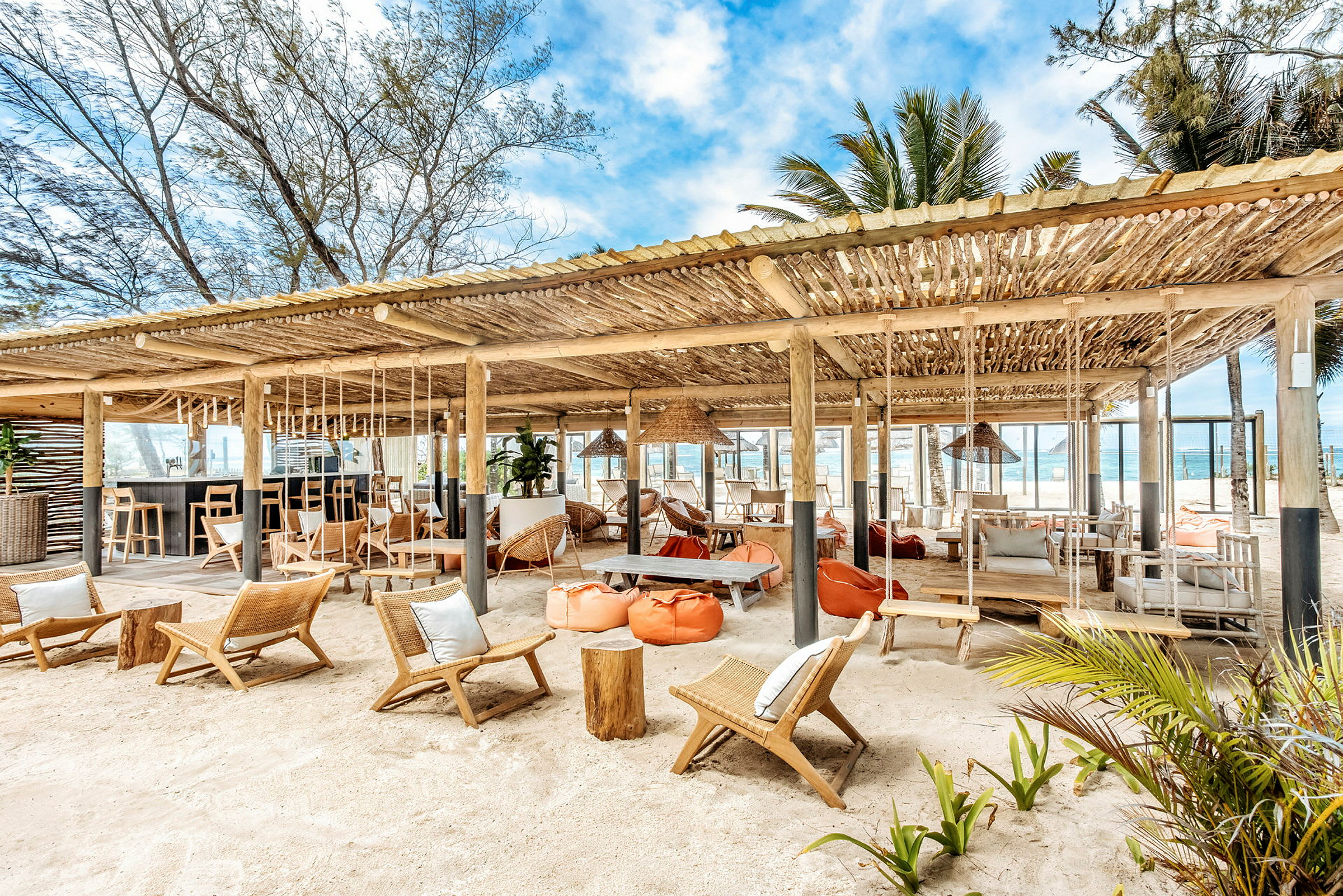 Strandbar med sittemøbler og hengekøyer under et tretak. (AI-generert tekst)