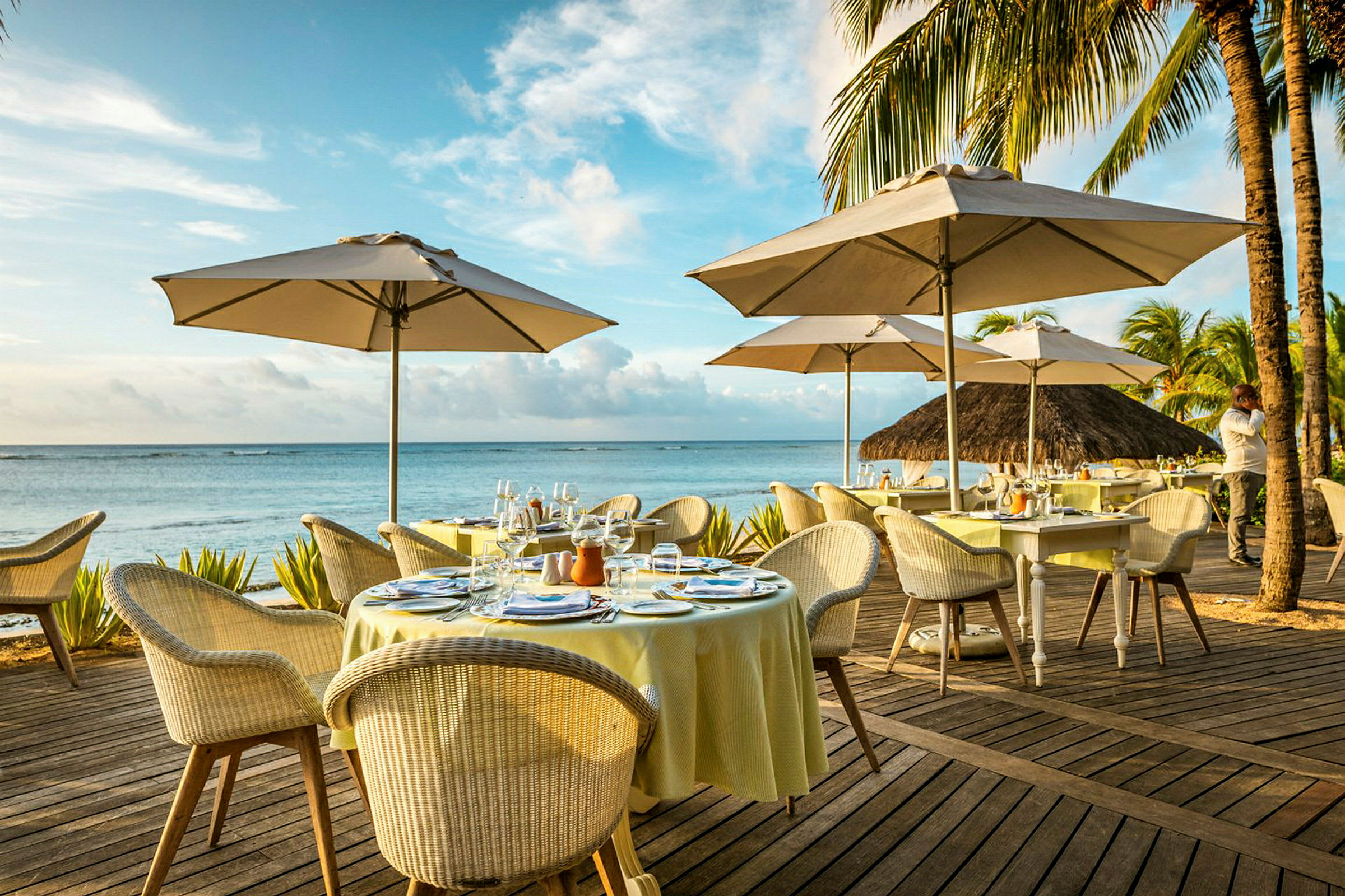 Utendørs terrasse ved havet med dekkede bord og parasoller. (AI-generert tekst)
